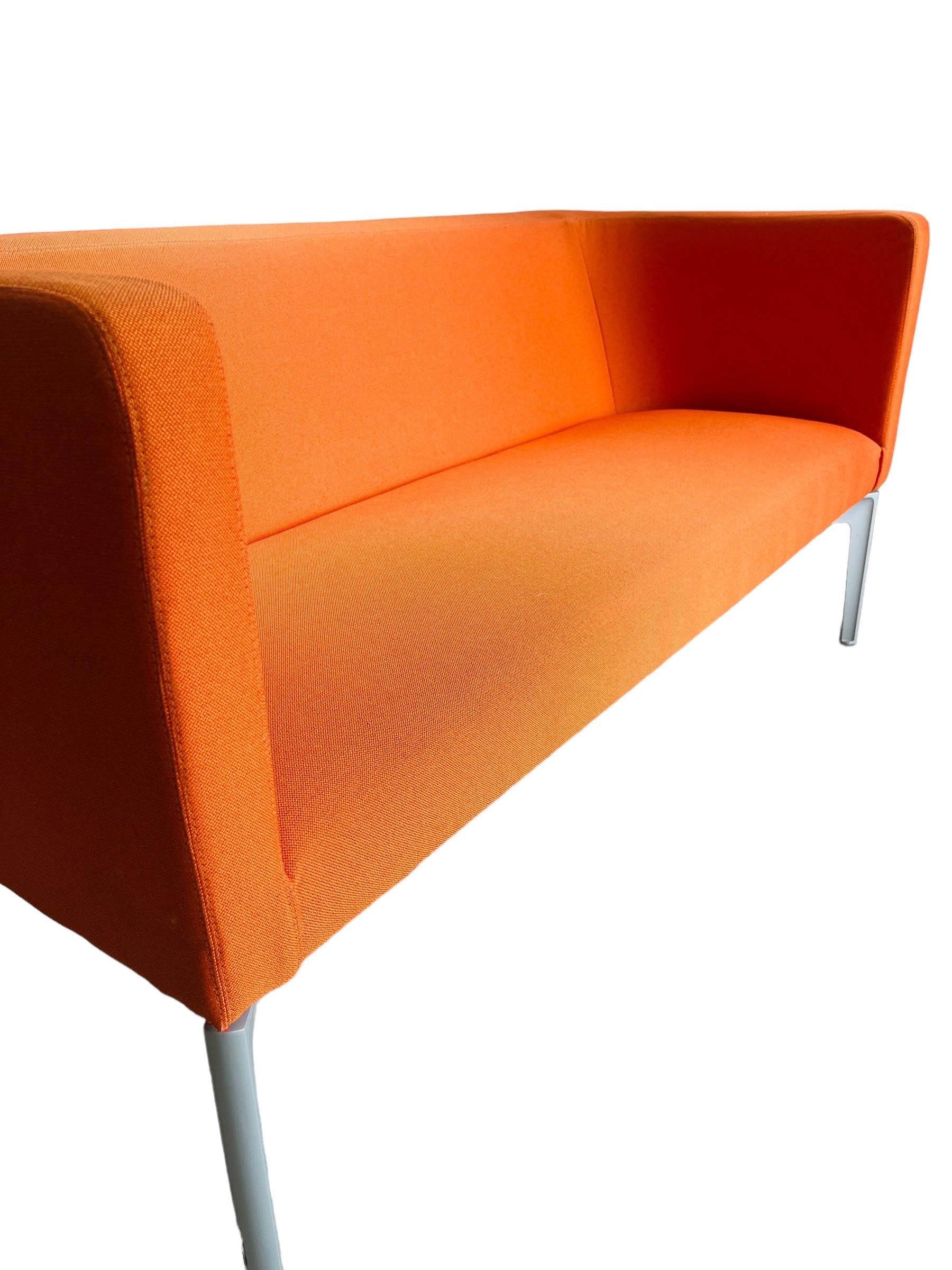Elevate your living space with the vibrant allure of the Steelcase Bivi Rumble Seat Collection Sofa. Upholstered in a striking orange hue, this sofa is designed not only to captivate but also to offer robust functionality in a compact design.