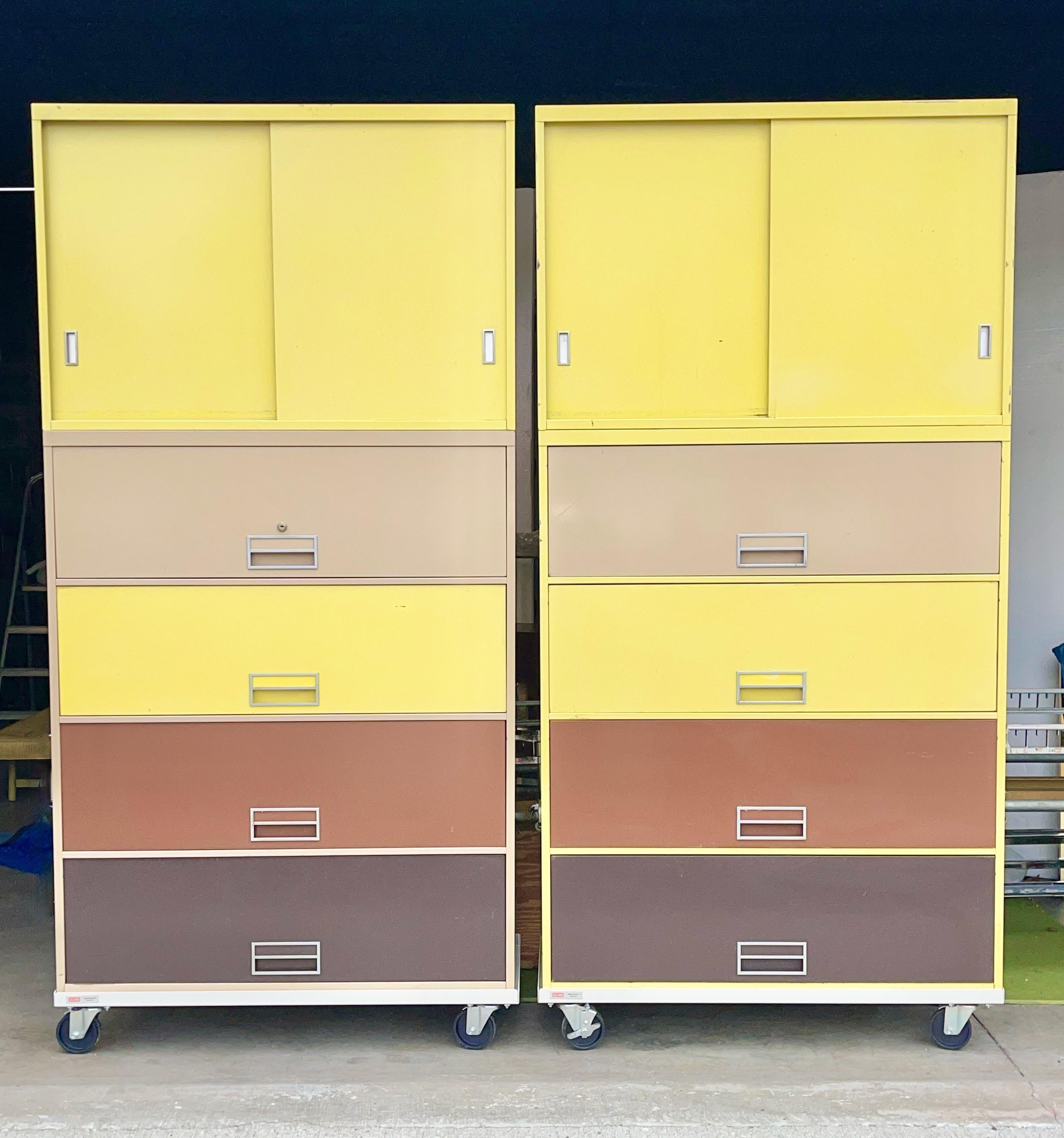 Two first edition 1966 Steelcase 'Broadside' lateral file cabinets each with four pull-out lateral file drawers and an upper cabinet with a removable single shelf and two sliding doors. 
The exterior of one file cabinet is yellow and the other is