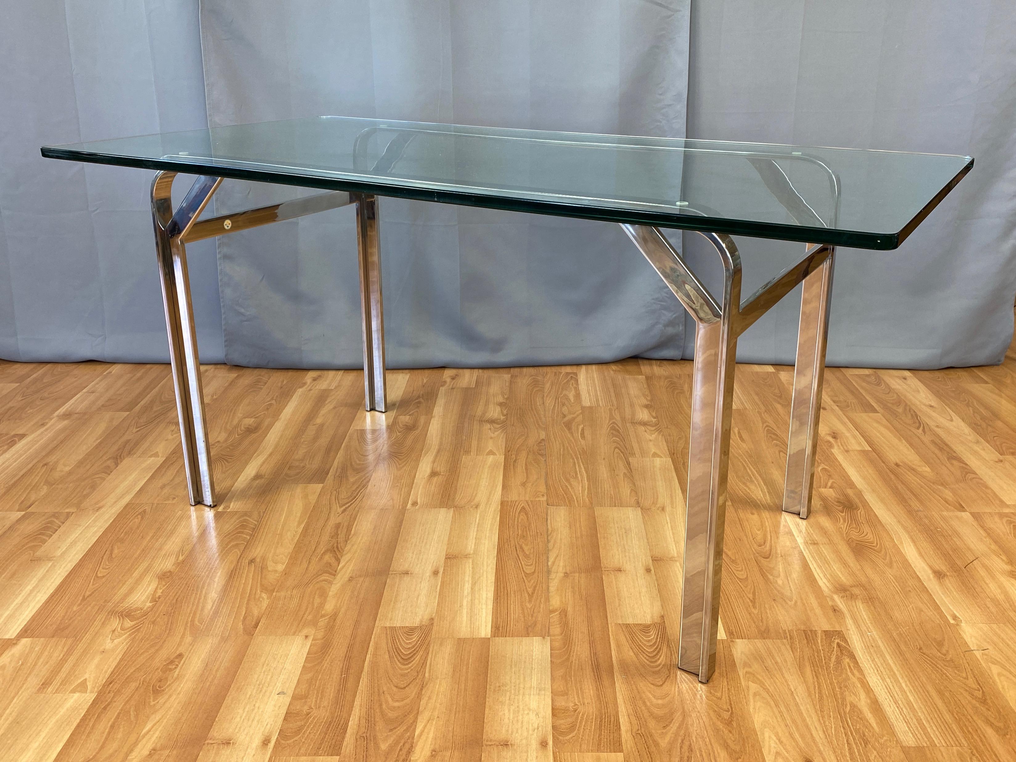 A very sleek and uncommon 1970s polished nickel-plated stainless steel desk or two-person dining table with original thick glass top, attributed to Steelcase.

Impressively crafted base with strikingly clean lines distinguished by angular supports