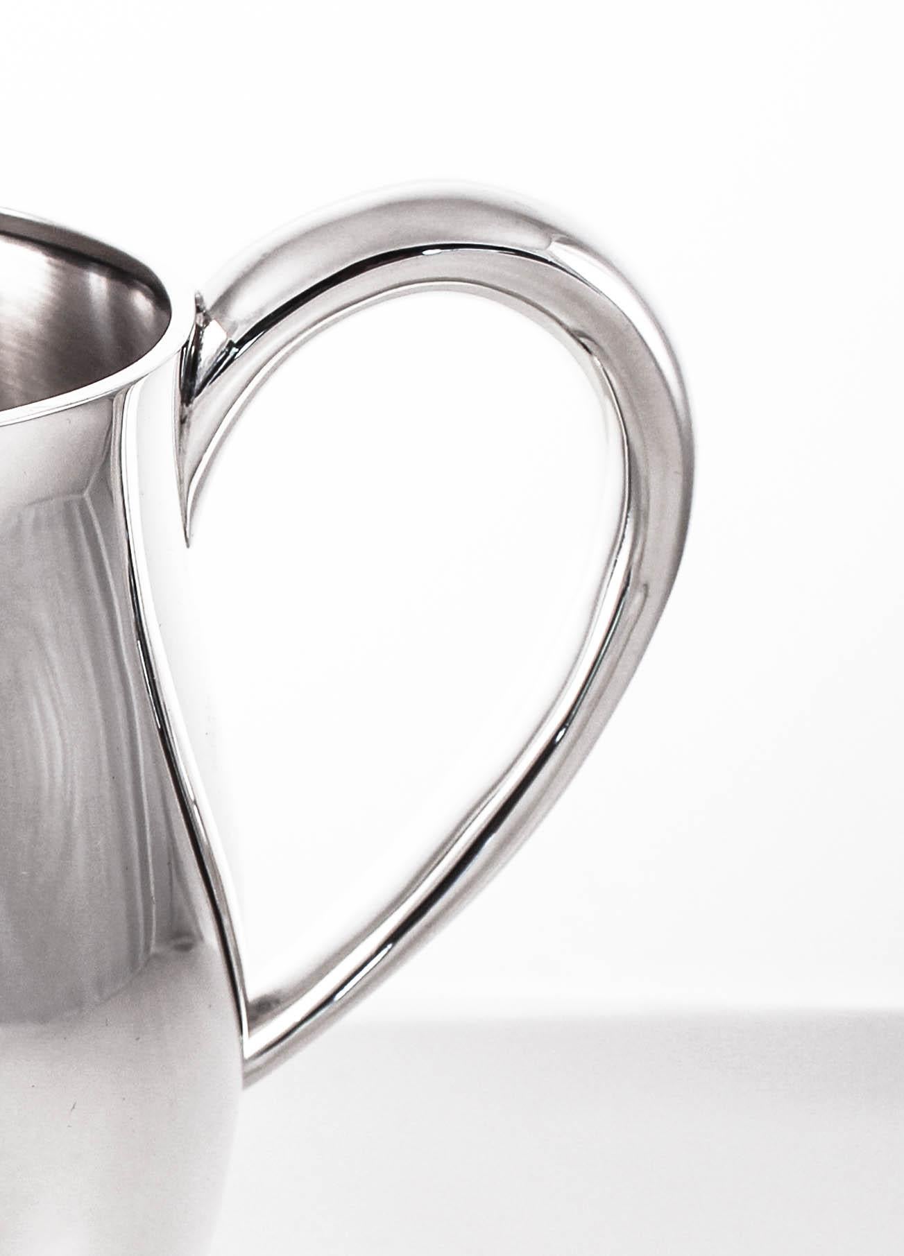 Offering a sterling silver water pitcher by Tuttle Silversmiths. It’s style and simplicity is reflective of the WWII period. Understated and without decoration, it was made during a time when elaborate decorative items were not popular. But these