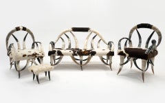 Canapé, deux chaises et un pouf en cuir de vache noir, marron et blanc de la marque Horn