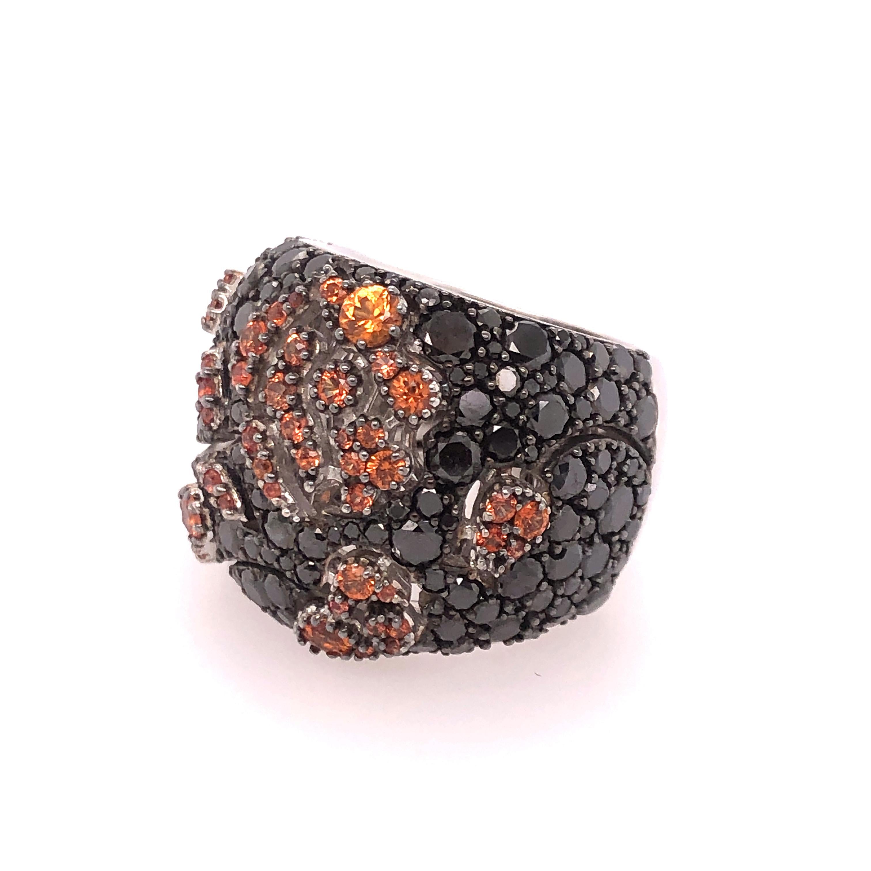 Dramatically designed by Stefan Hafner with the contrast of Black and Orange Sapphires this floral motif ring demands to be worn. 
Orange Sapphires create the illusion of flowers across the deep background of black sapphires. The negative spaces in