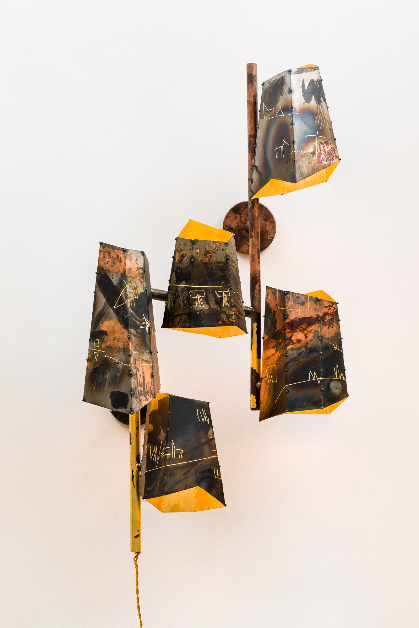 Five hand-built steel shades are mounted onto vertical posts at various heights creating an organic cluster of asymmetric forms. Each shade is cut and welded individually, before patinas are applied. An abstract language of semi-pictographic images