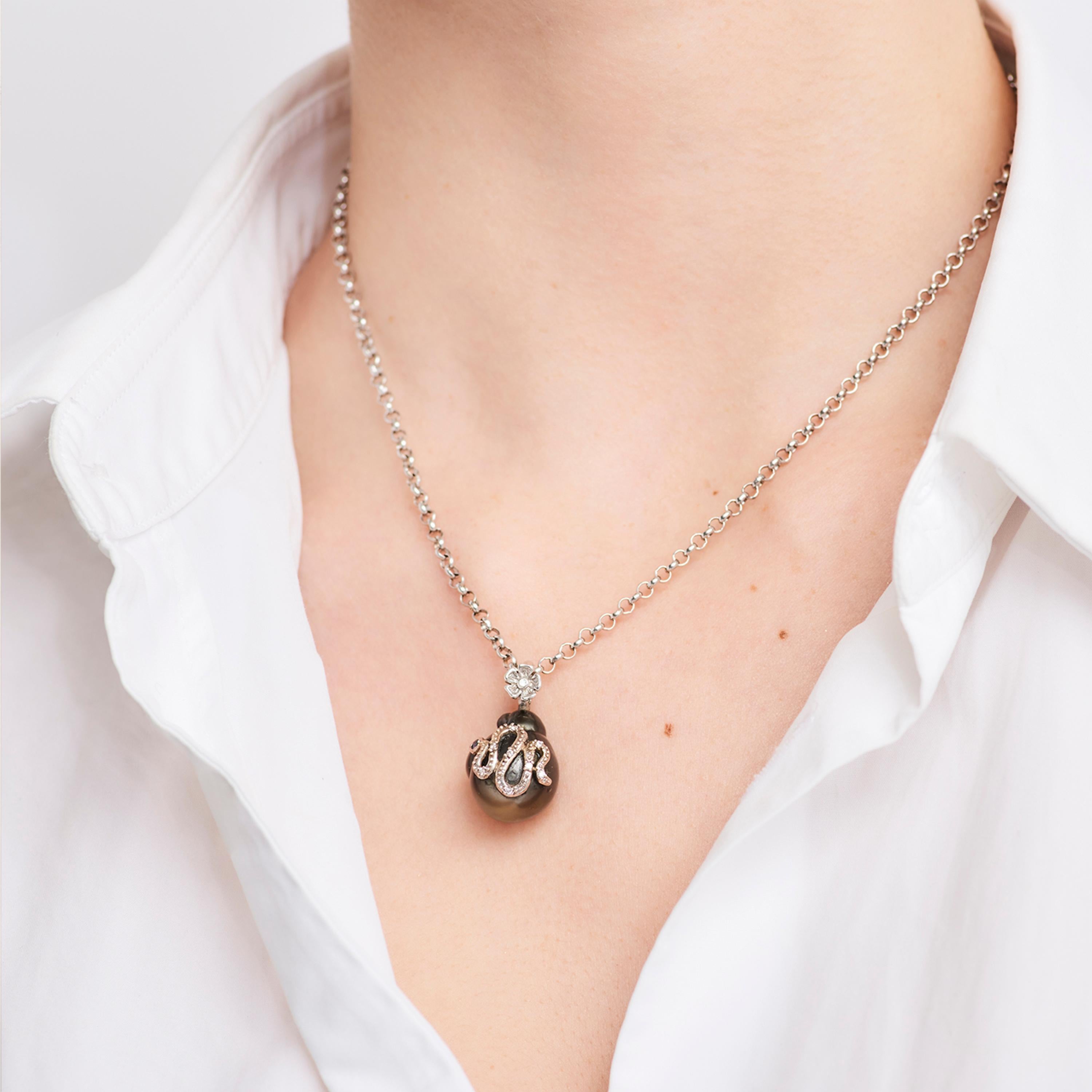 Stella Flame’s Baroque Tahitian Pearl Serpent Pendant is crafted from 18 karat white gold. A serpent embellished with white diamonds (0.2cts) and black diamonds (0.3cts) is set on a beautiful baroque Tahitian pearl. A delicate flower juxtaposes the
