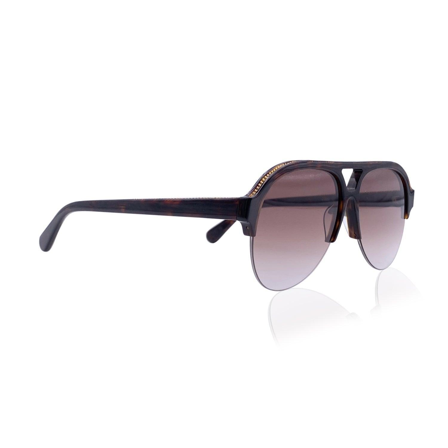 Lunettes de soleil aviateur Stella McCartney 'Falabella' mod. SC0030S - C.C.. Elles sont dotées d'une monture marron à demi-bord en matériau bio. Lentilles marron dégradées. Chaînes en métal doré sur les bords supérieurs. Mod & refs : mod. SC0030S -