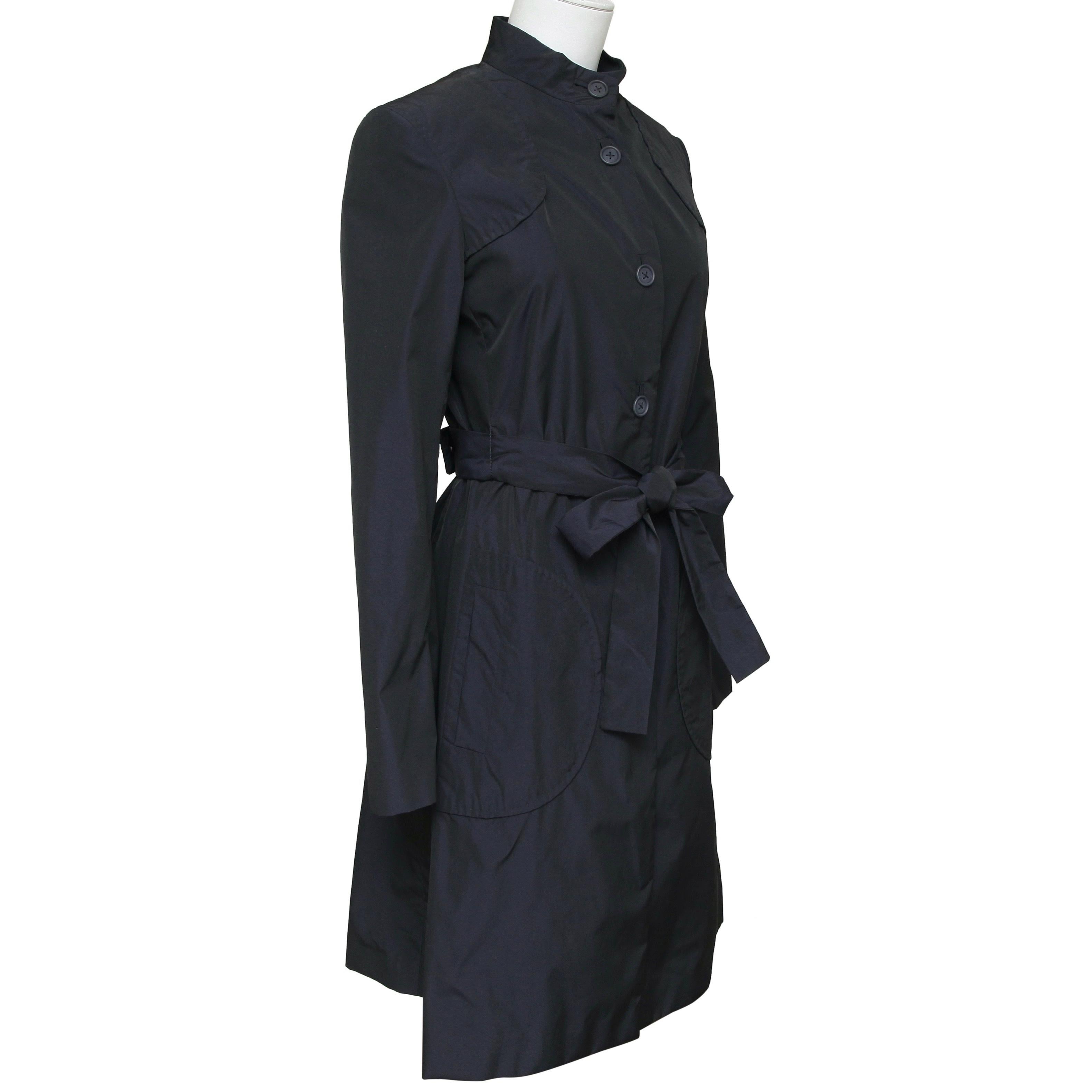 GUARANTEED AUTHENTIC STELLA MCCARTNEY NAVY TRENCH COAT

Details:
- Dark navy blue mid-length trench style coat.
- Stand up neckline.
- Buttons down front.
- Attached sash belt.
- Front and back flaps.

Material: 100% Polyester

Size: