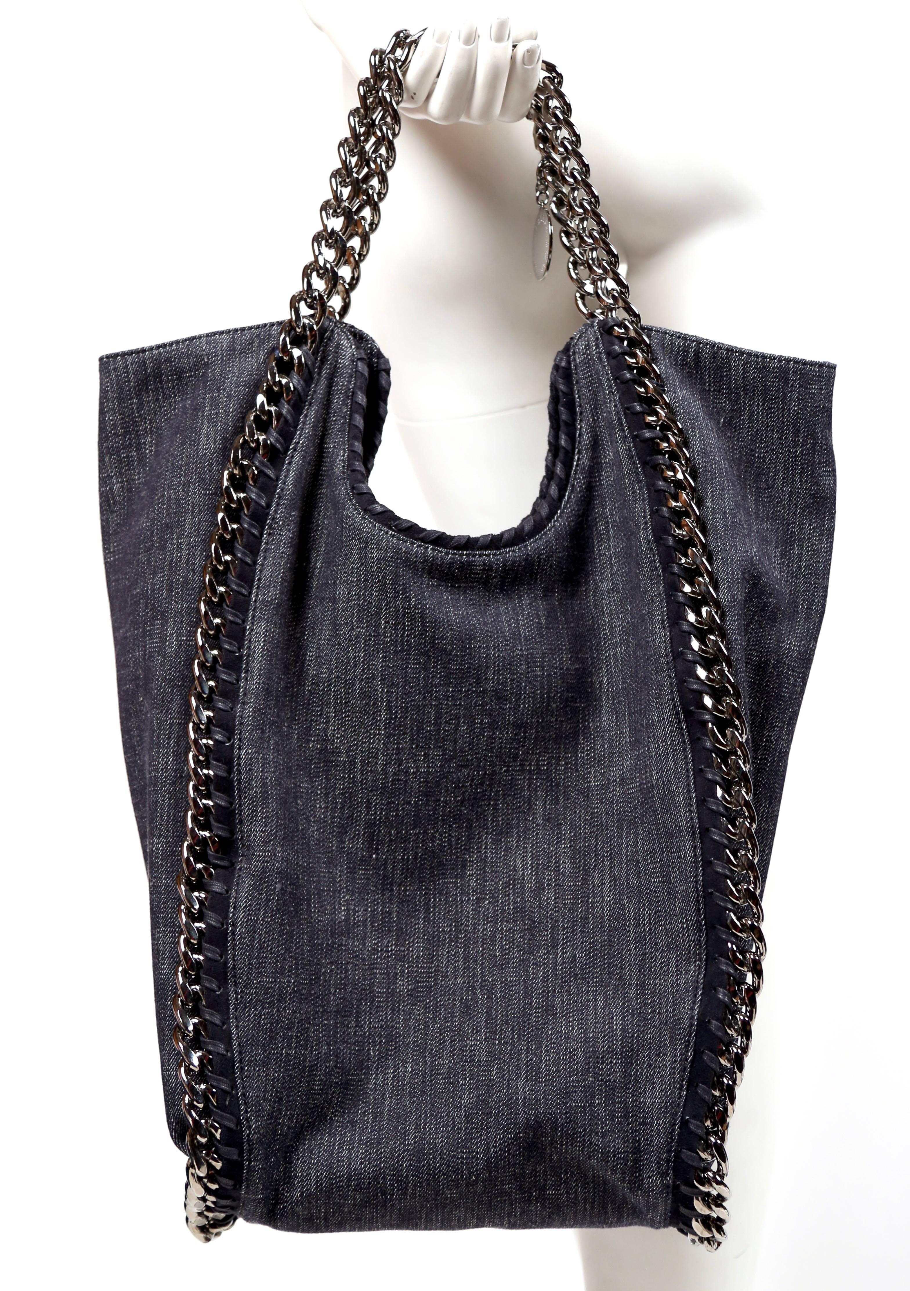 Dark denim tote bag with silver-tone hardware, dual chain-link shoulder straps, whipstitching and chain-link details designed by Stella McCartney. Approximate measurements: width 16.5