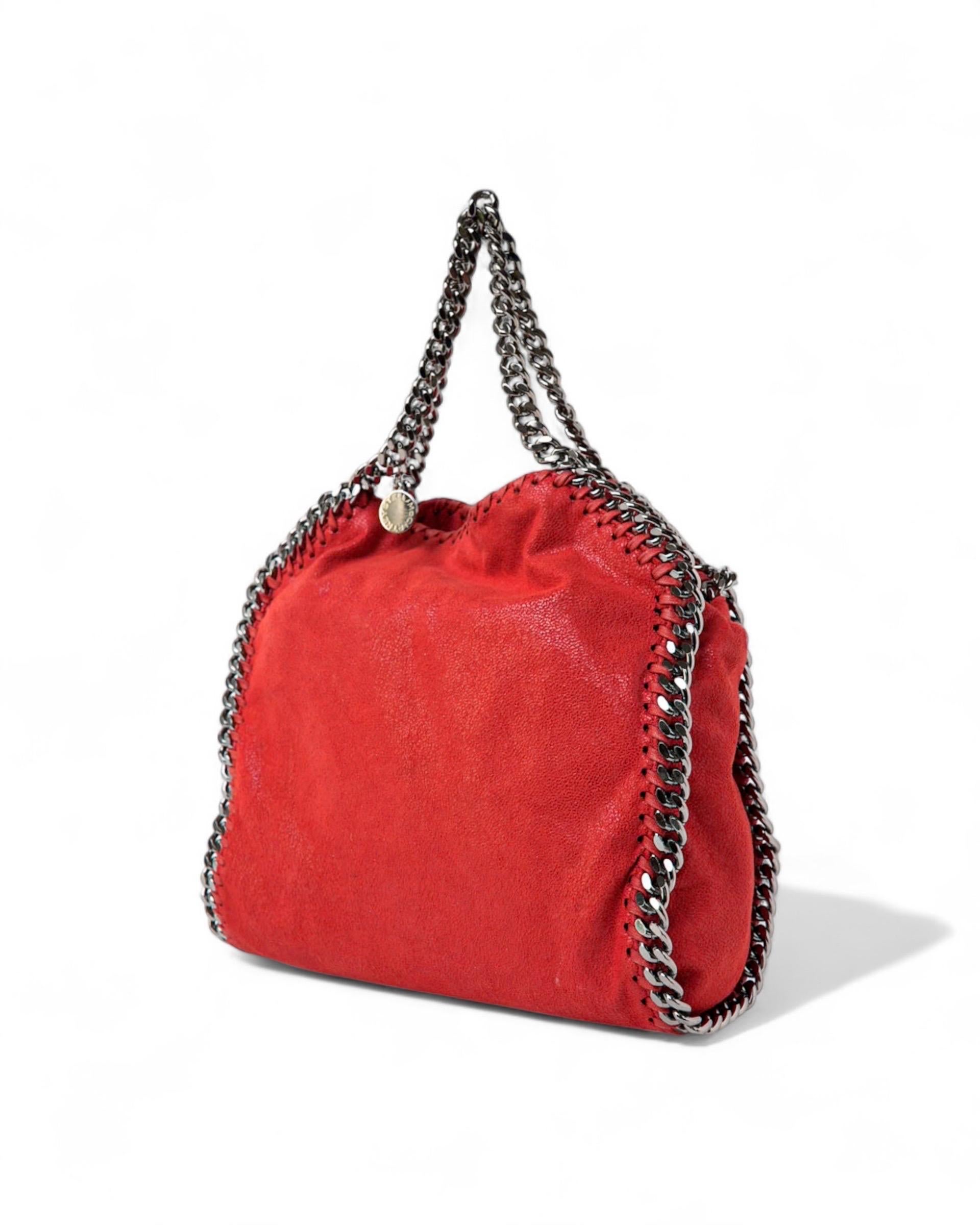 Borsa firmata Stella McCarthney, modello Falabella 3 Chain, realizzata in tessuto scamosciato nella colorazione rossa con hardware argentati. Dotata di una chiusura calamitata. Internamente rivestita in tessuto logato tono su tono con comoda tasca,