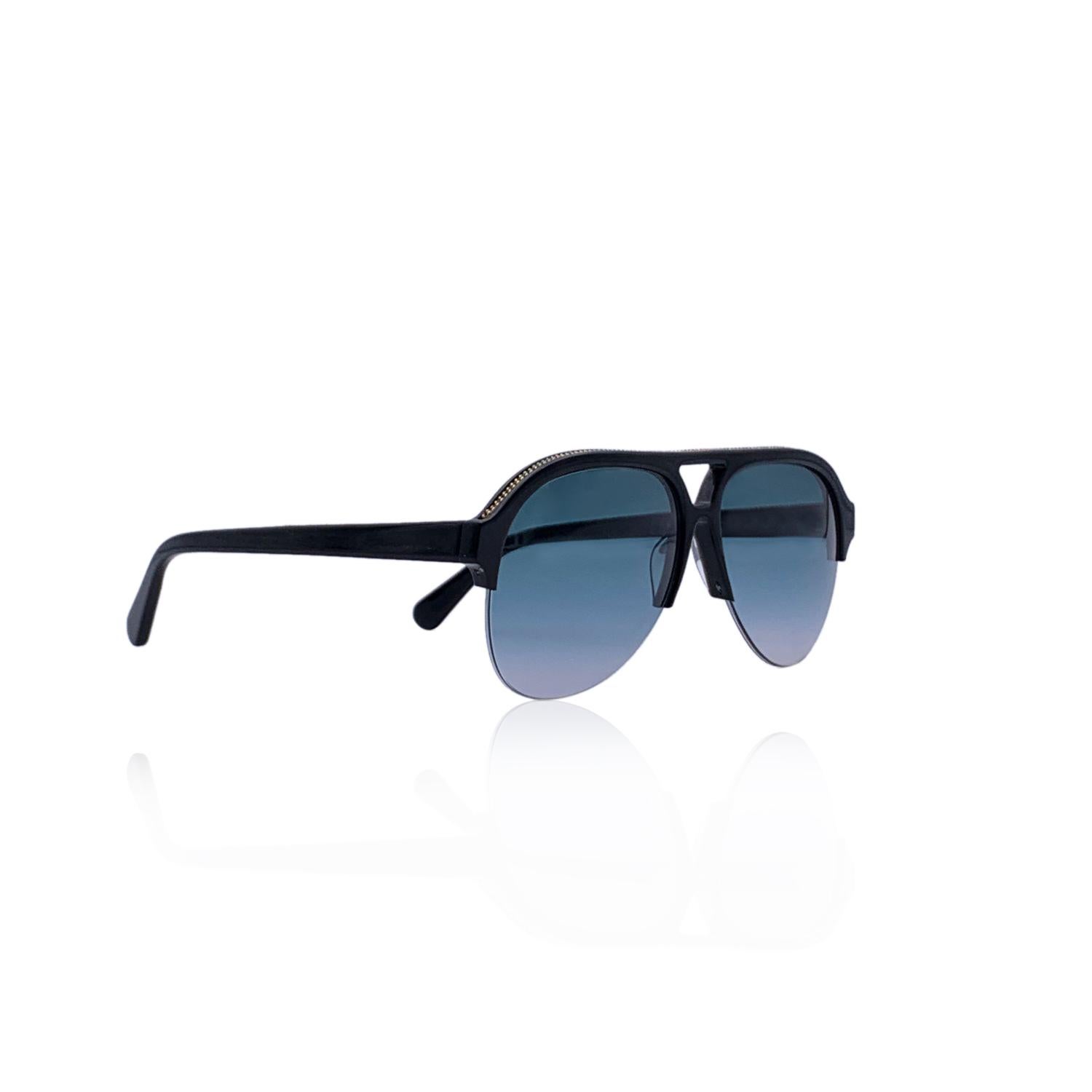 Lunettes de soleil aviateur Stella McCartney 'Falabella' mod. SC0030S - c.001. Elles présentent une monture noire à demi-cercle en matériau bio. Verres bleus dégradés. Détails de la chaîne en métal doré le long des bords supérieurs. Mod & refs. :