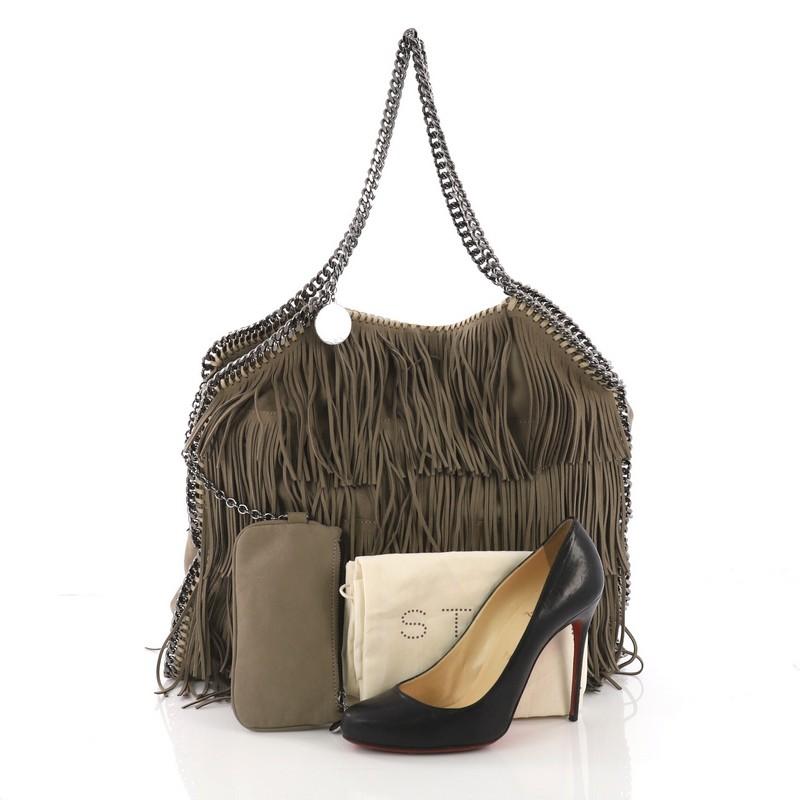 This Stella McCartney Falabella Fringe Tote Faux Suede Large, crafted in taupe faux suede, features slinky chain handles, signature curb chain trims, whipstitched edges, Stella McCartney logo disc charm, and gunmetal-tone hardware. Its magnetic