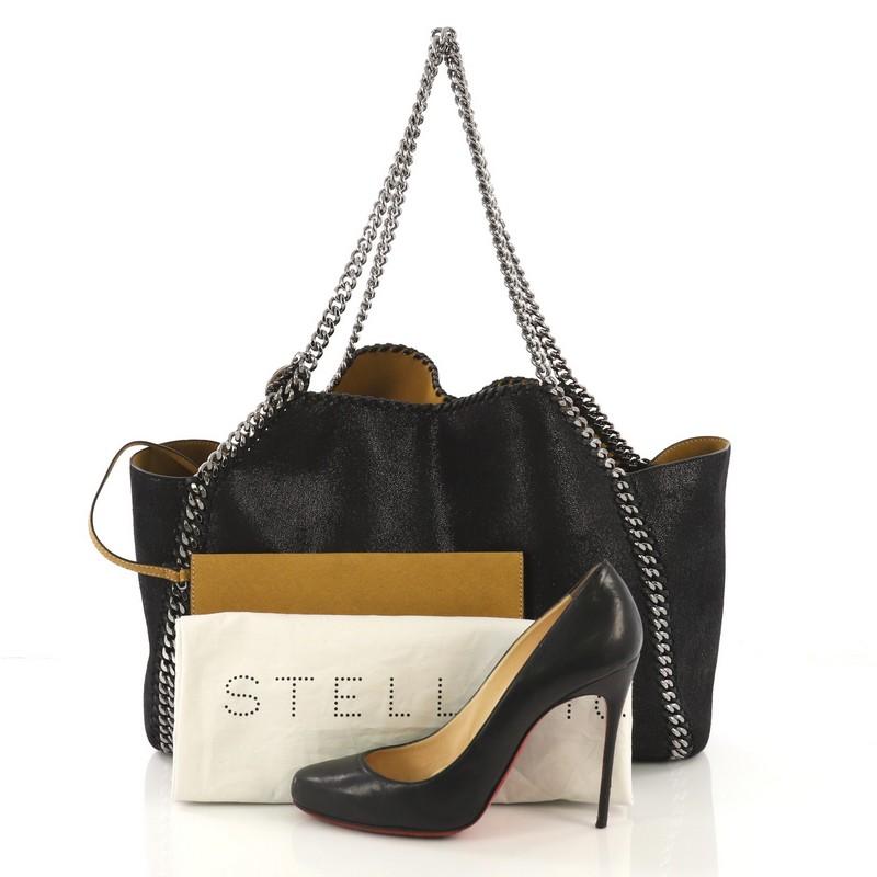 This Stella McCartney Falabella Reversible Tote Shaggy Deer Large, crafted in black shaggy deer, features chain link strap and trim, whipstitched edges, hanging logo disc, and gunmetal-tone hardware. It opens to a yellow microfiber interior. **Note: