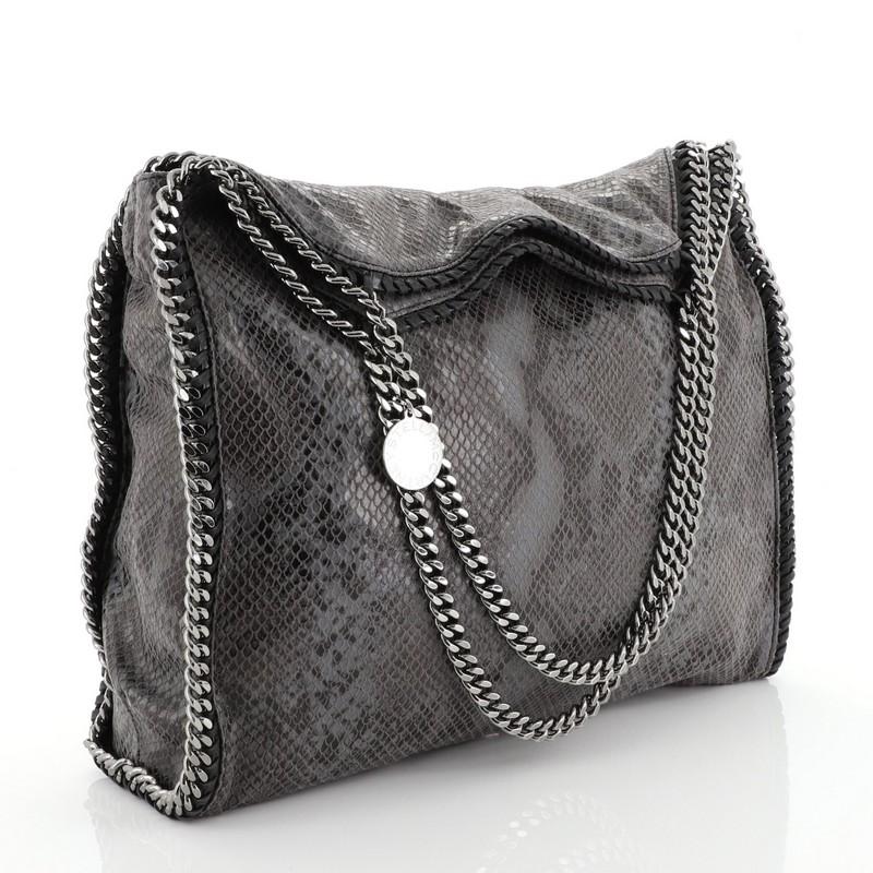 This Stella McCartney Falabella Tote Faux Snakeskin Large, crafted from gray faux snakeskin, features chain link handles and trim, whipstitched edges, hanging logo disc, and gunmetal-tone hardware. Its magnetic snap closure opens to a black fabric