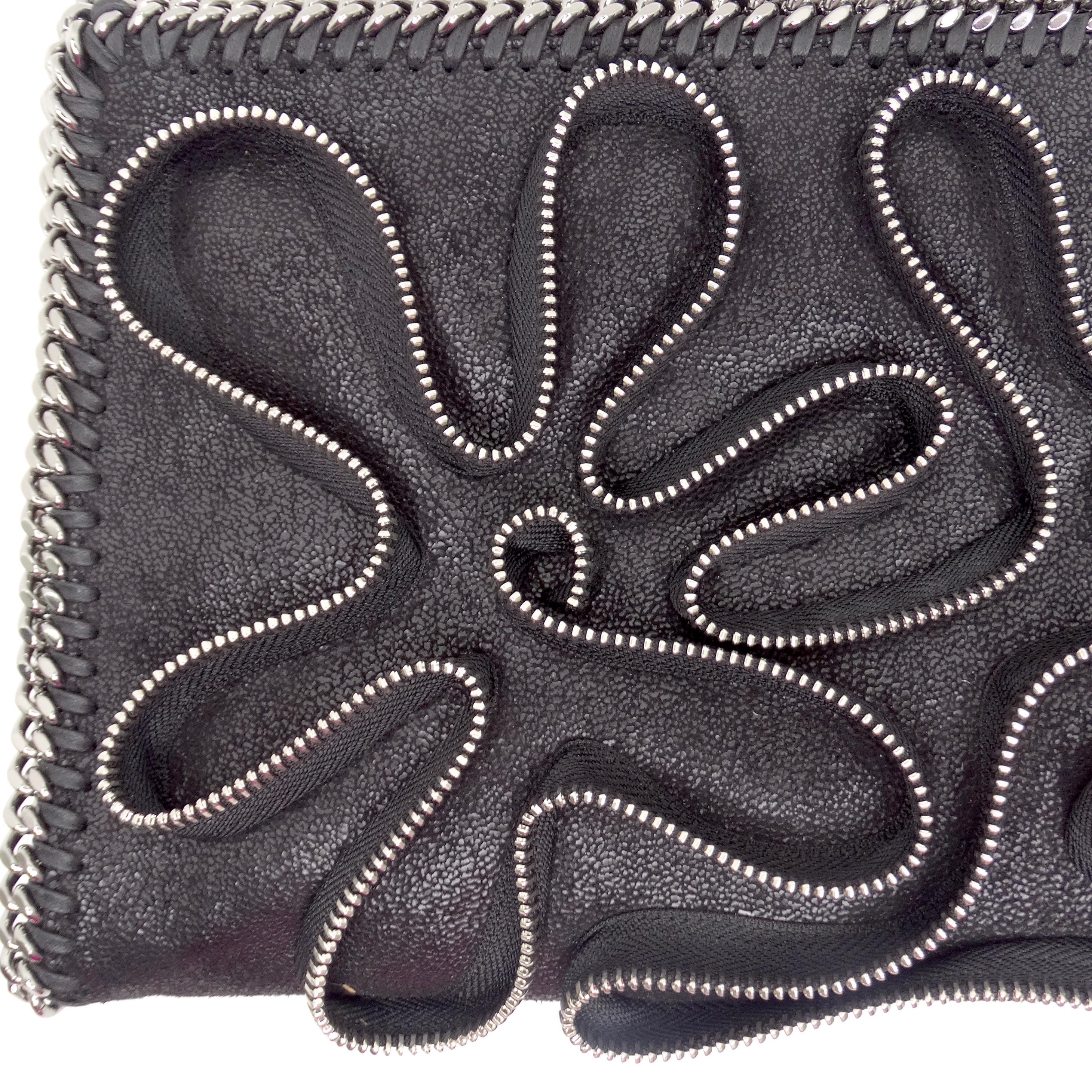 Die Stella McCartney Falabella Zipper Trim Fold Over Clutch ist ein umwerfendes und einzigartiges Accessoire, das mühelos kantiges Flair mit zeitloser Eleganz verbindet. Diese aus luxuriösem schwarzem Kunstleder gefertigte Clutch zum Umklappen