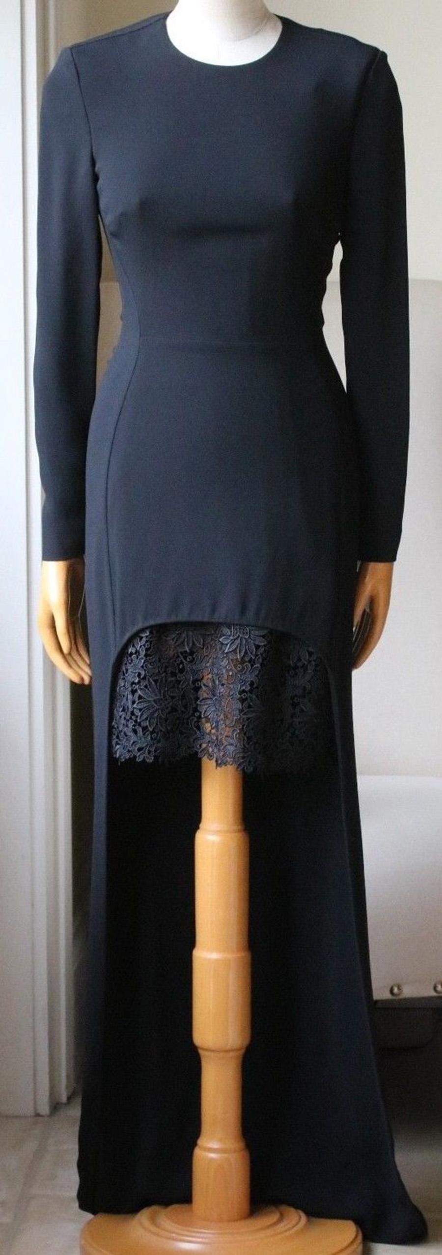 The black Cady fabric is juxtaposed with a thick lace underskirt, while the contrasting hem elongates the legs. This black Cady dress has a close fitting round-neck, long sleeves and features a longer length back and lace trimmed shorter front hem.