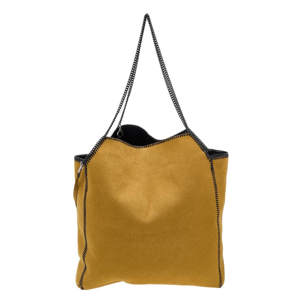 This Falabella shopper tote from the House of Stella McCartney will make your dream of owning a lavish handbag come true! This tote is durable and stylish in its structure. It has been made using mustard-black faux suede and faux leather, with chain