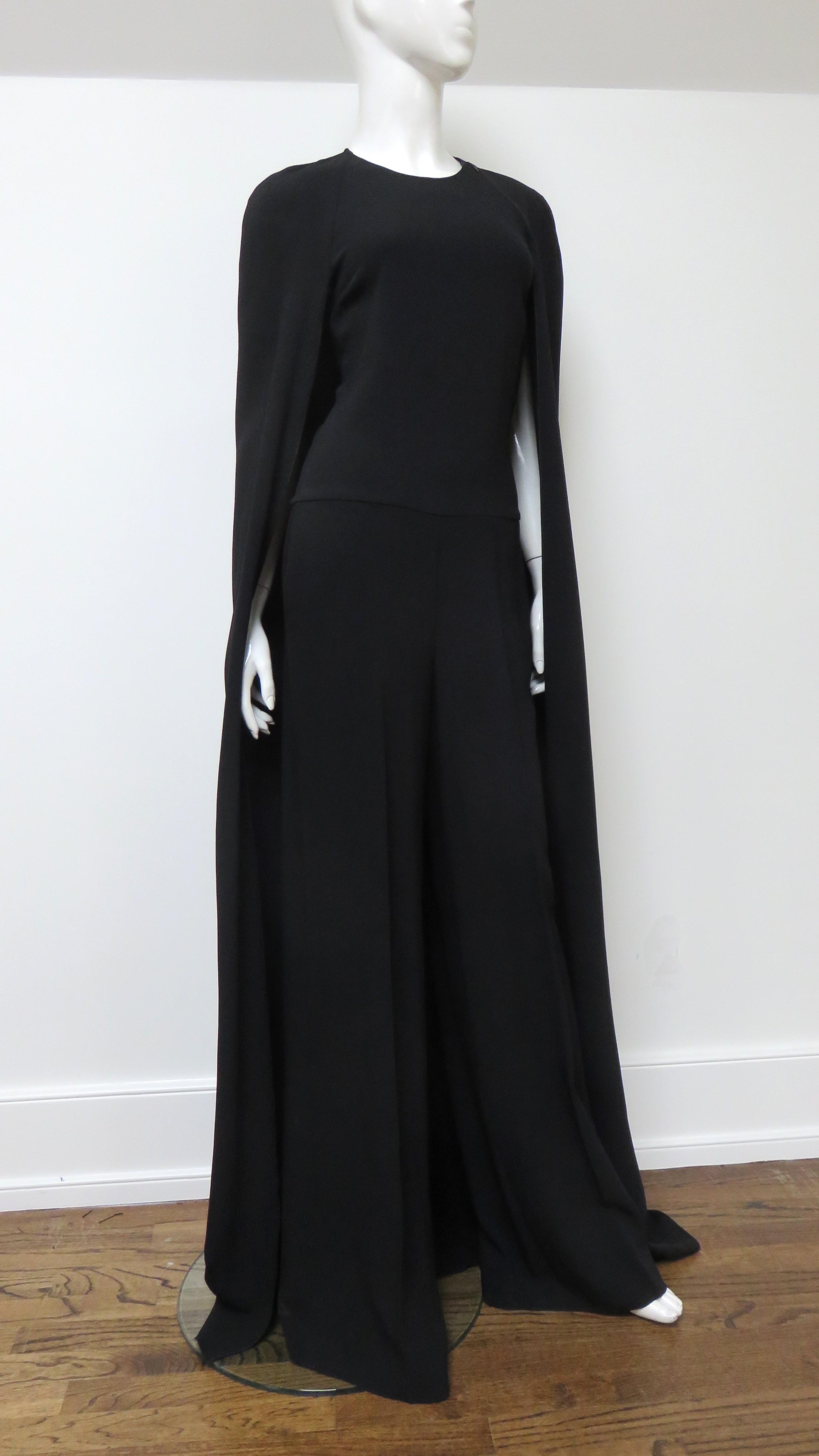 A fabulous black with a bit of stretch silky jumpsuit by Stella McCartney.  It is sleeveless, has a crew neckline and full legs with hip side seam pockets. An attached cape drapes over the shoulders, arms and back the length of the jumpsuit. There