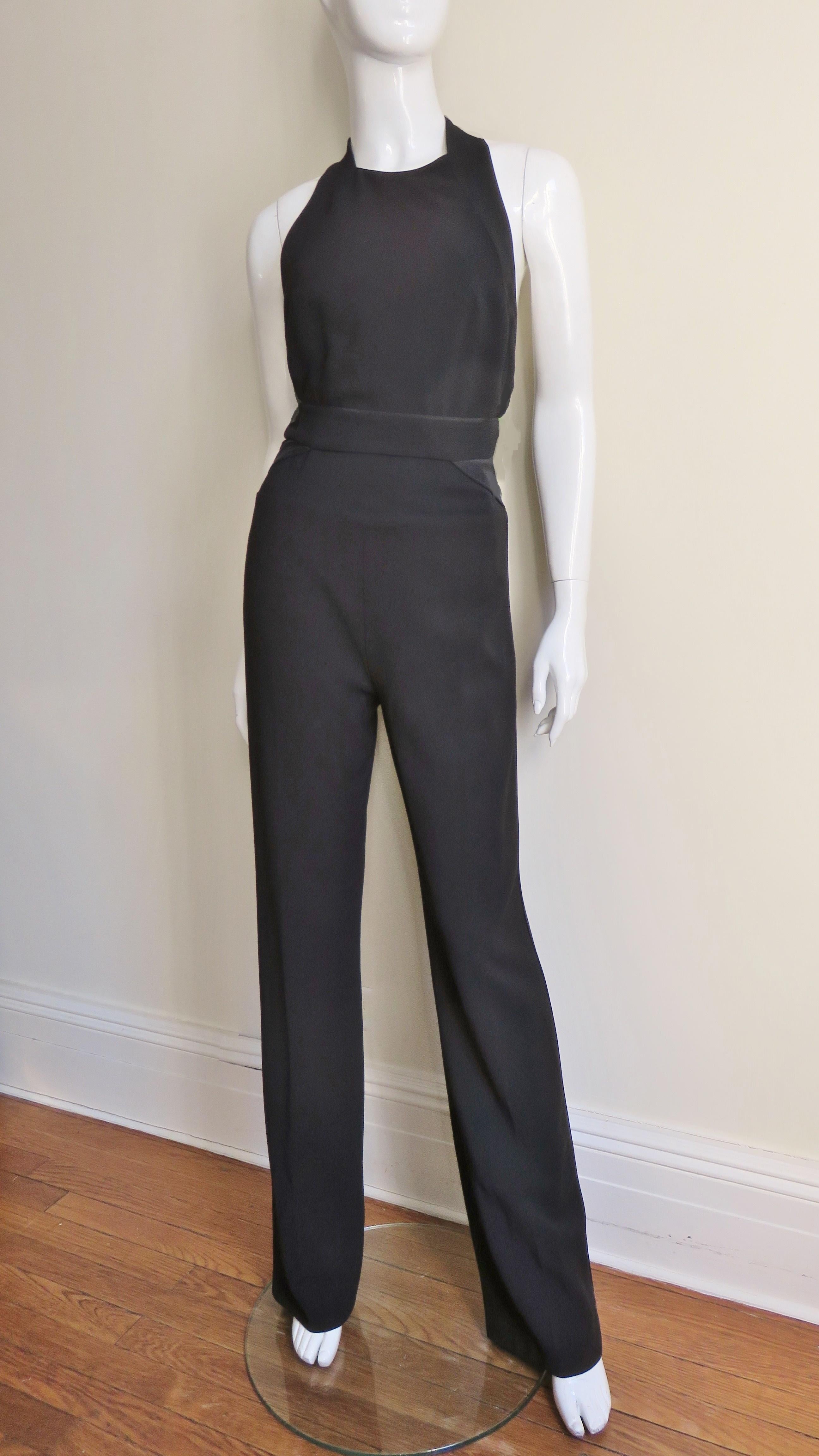 A fabulous black jumpsuit from Stella McCartney.  It has a crew neck, cut in shoulders, racerback and a band at the waist. The legs are straight and have matching piping along the outside of each leg.  It has a back zipper and is lined in black