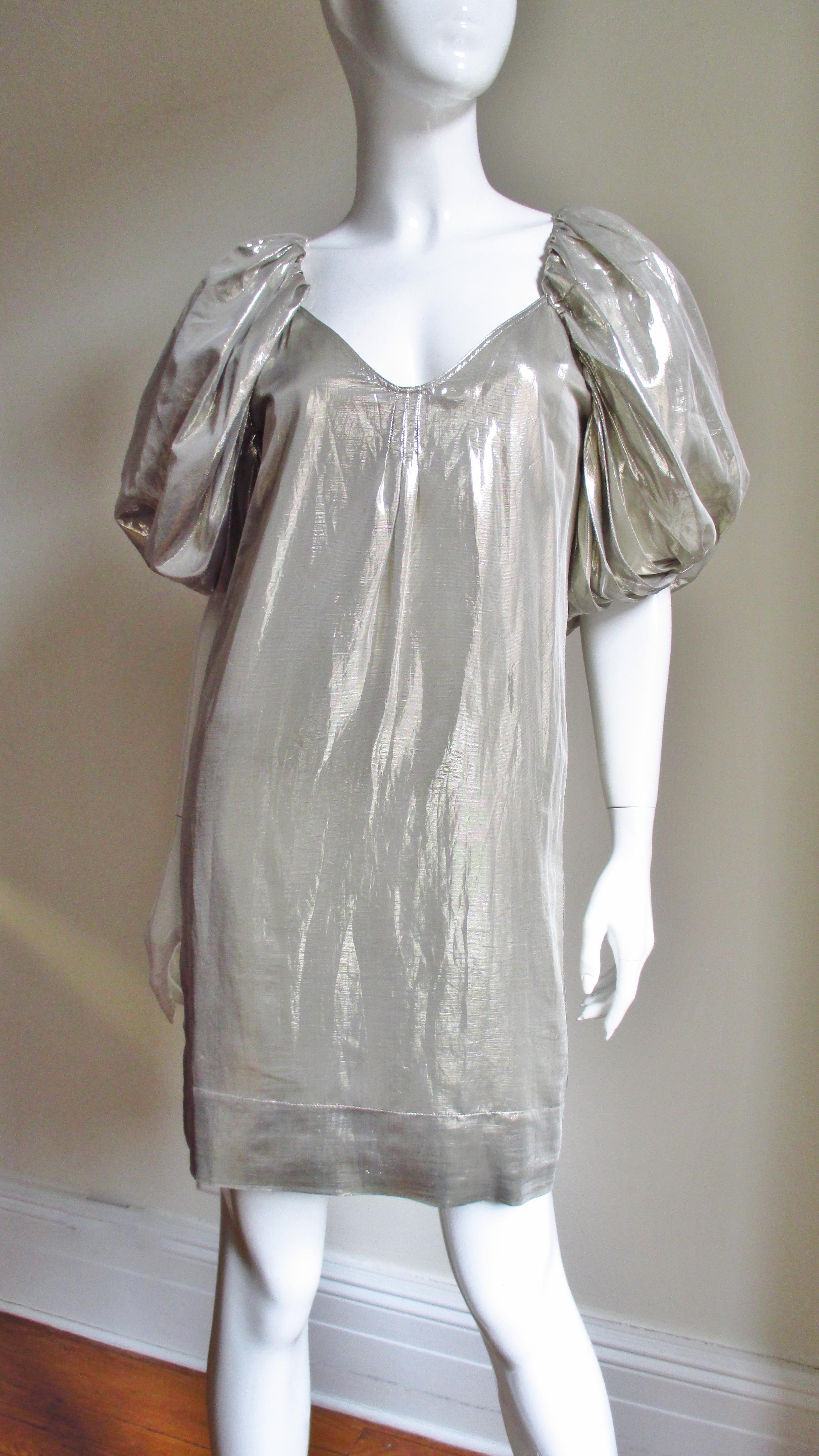 A pretty silver silk dress from Stella McCartney's S/S 2007 collection.  It has a V neck and full elbow length sleeves. It is fully lined and slips on over the head.  
Fits sizes Extra Small, Small.

Bust  34