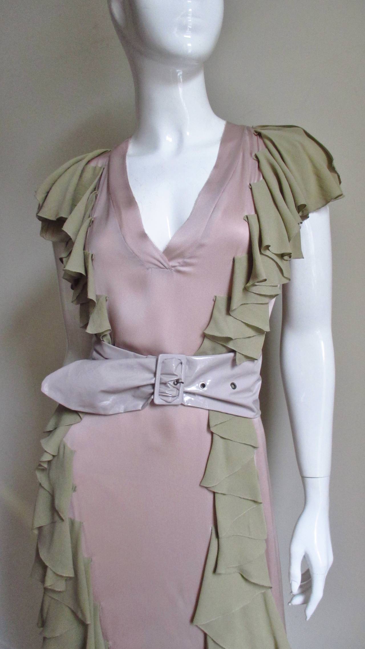 A pretty dress in beautiful combination of pink silk charmeuse with olive ruffles from Stella McCartney. It is a simple V neck dress enhanced with ruffles down the entire length of the dress on each side of the front and back.  The dress is