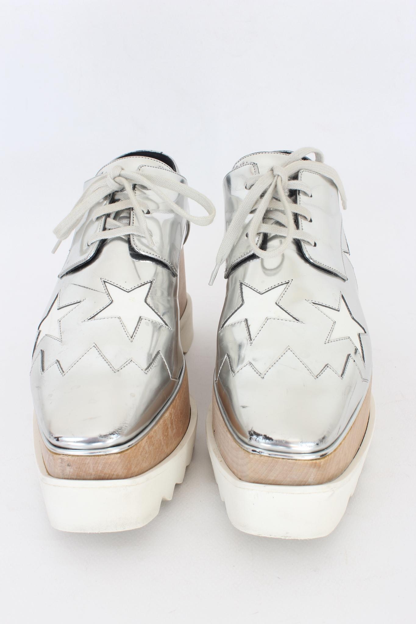 Stella McCartney 2020s Elyse sneaker shoe. Silver eco-leather shoe with white leather stars. Square toe, lace closure. Beige wooden midsole and serrated white rubber outsole. Made in Italy.

Code: 363998

Size: 40, 5 It 10.5 Us 7.5 Uk

Heel height: