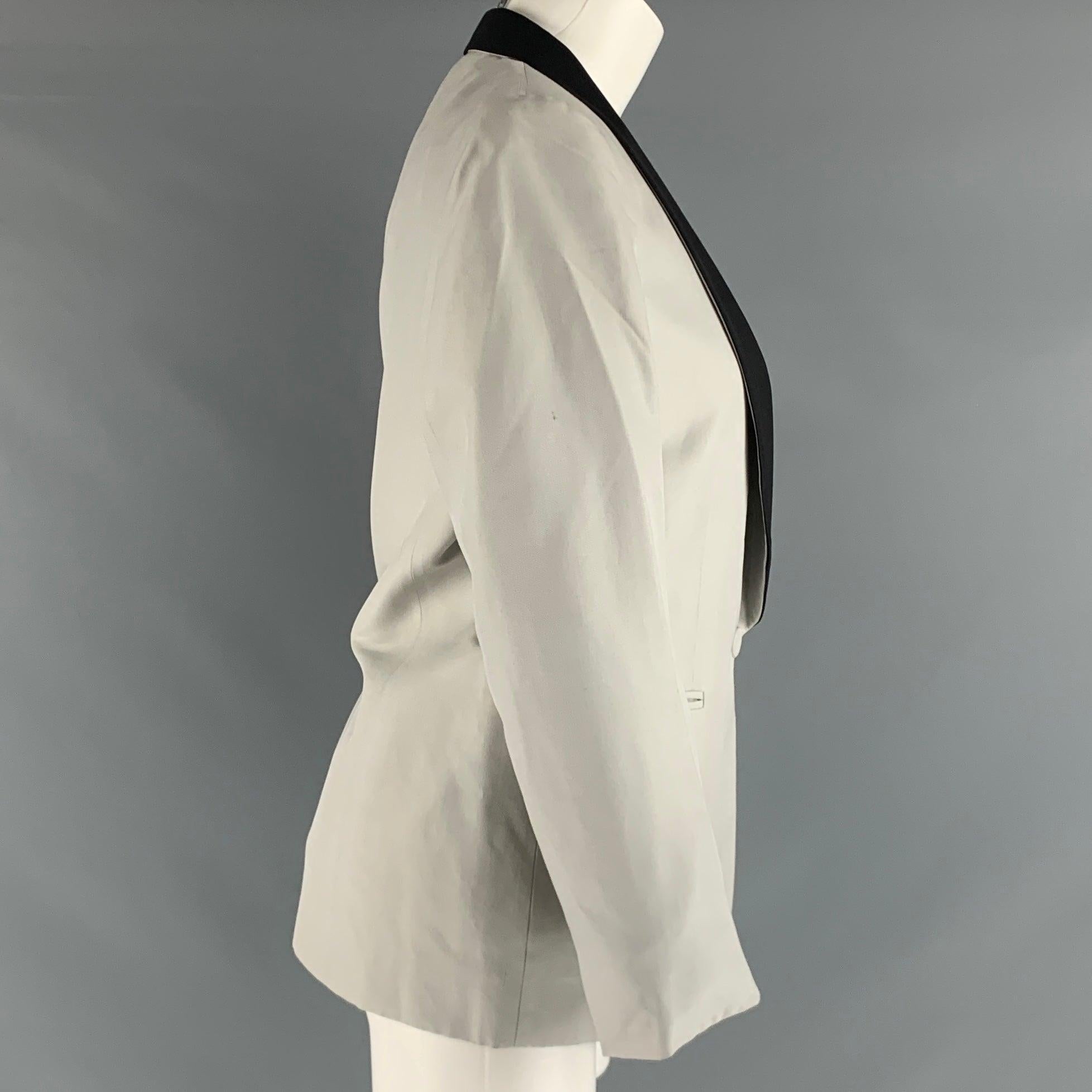 Ce blazer STELLA McCARTNEY en soie tissée argentée présente un revers châle noir, des poches passepoilées et une fermeture à bouton unique. Fabriqué en Italie. Très bon état. Taches mineures, voir la photo. 

Marqué :   44 

Mesures : 
 
Épaule :