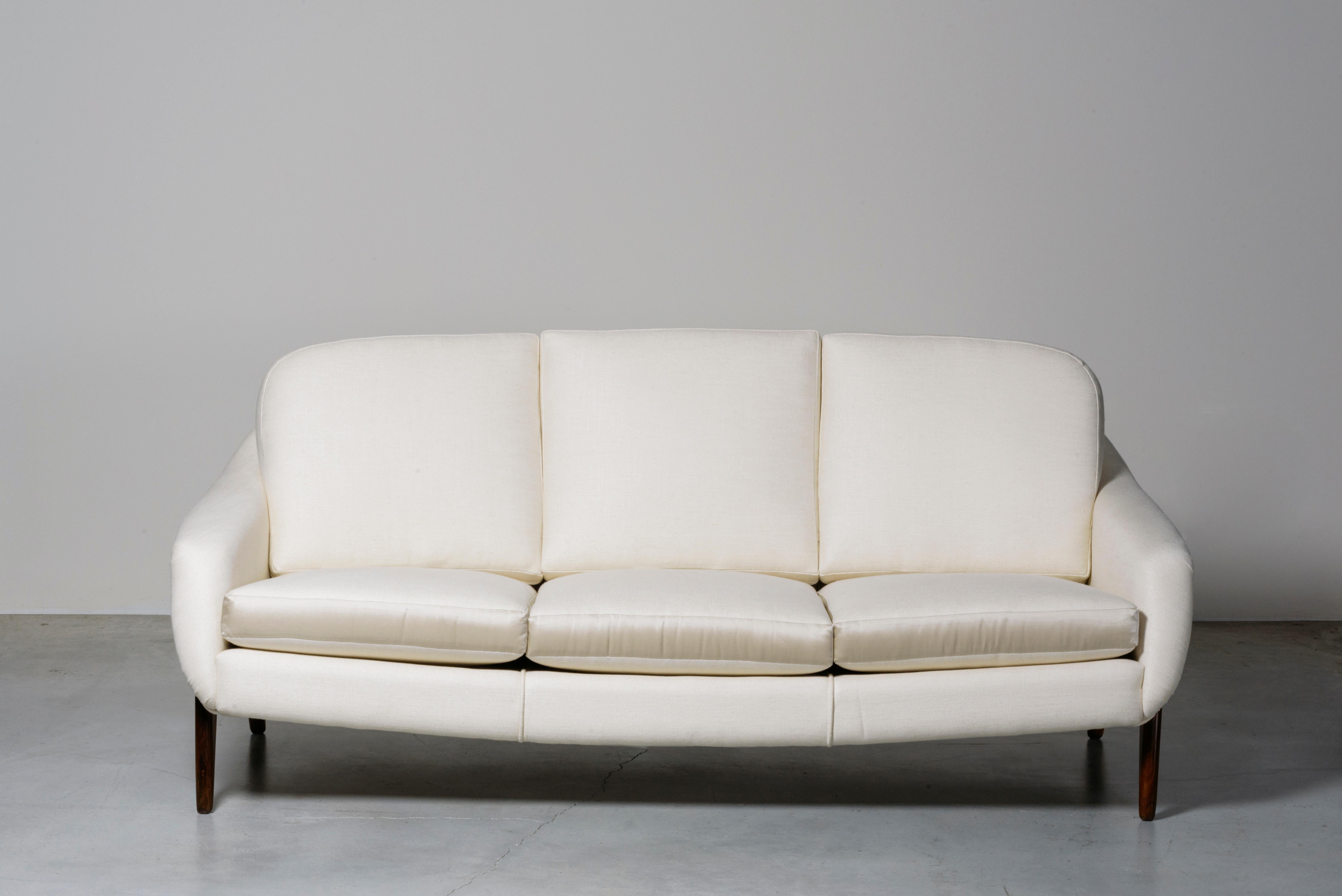 Stella Sofa von Sergio Rodrigues. Brasilien, 1965.
Hergestellt von Oca. Das Beispiel ist mit einem Steuerstempel der brasilianischen Regierung versehen. Massivholz, Polsterung aus Stoff. Maße: 190 x 90 x H 76 Sitz H 35 cm. 74,9 x 35,5 x H 29,9 Sitz