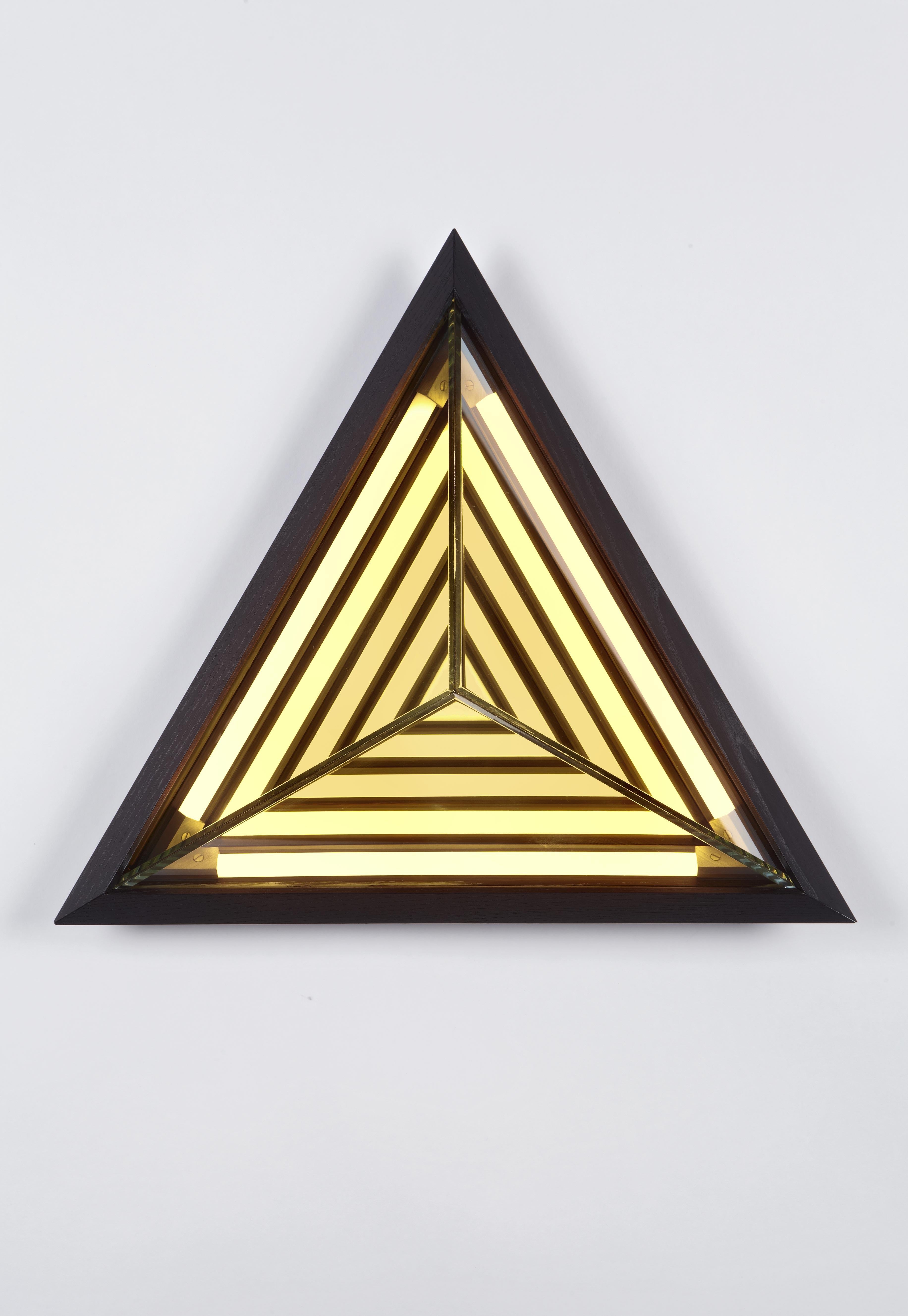 Inspired by his early work, this sconce is named after the painter Frank Stella. When illuminated, its half-mirrored glass diffuser reveals a series of nested geometric shapes. Stella creates the impression of infinite volume within a finite