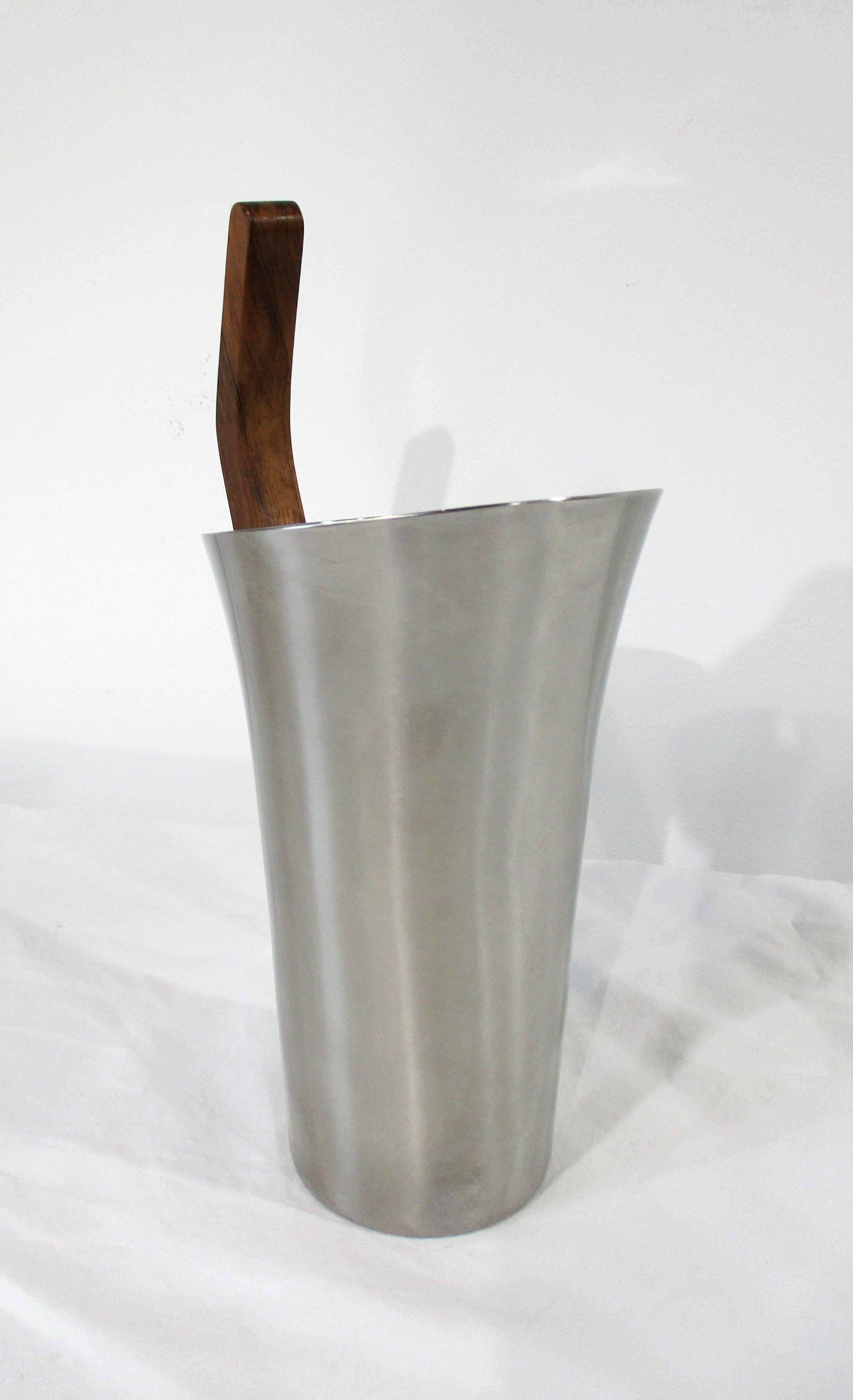 A stunning sculptural stainless-steel martini pitcher with built in strainer to the pour spout. The curved handle is fashioned out of Brazilian rosewood designed by the iconic Arne Jacobsen for Stelton Denmark. A superb quality example of fine