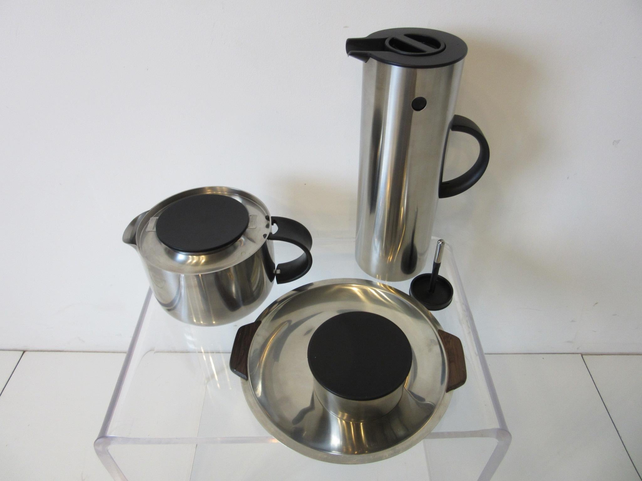 A four-piece set featuring a stainless steel water / coffee vacuum jug, with two tops, tea pot with strainer and lid, sugar bowl with lid and a small stainless tray having rosewood handles including the original bag all marked made in Denmark by