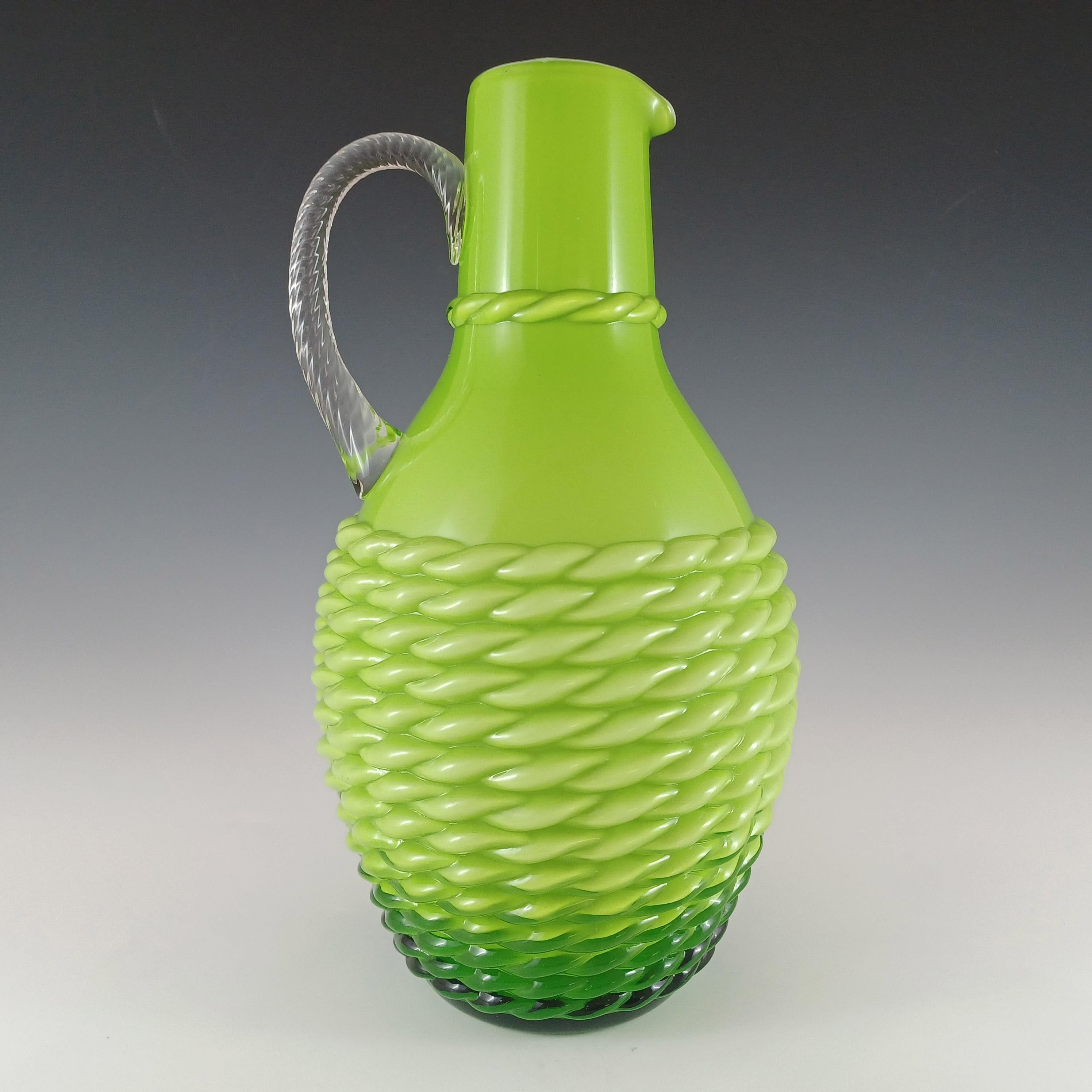 Grüne Retro-Glasvase im Stil eines Kruges mit halb-opakem weißem Innengehäuse, appliziertem Klarglasgriff und ausgeprägtem Korbflechtmuster. Hergestellt von der Fabrik Stelvia in der italienischen Region Empoli. Die Identifizierung stammt von einem