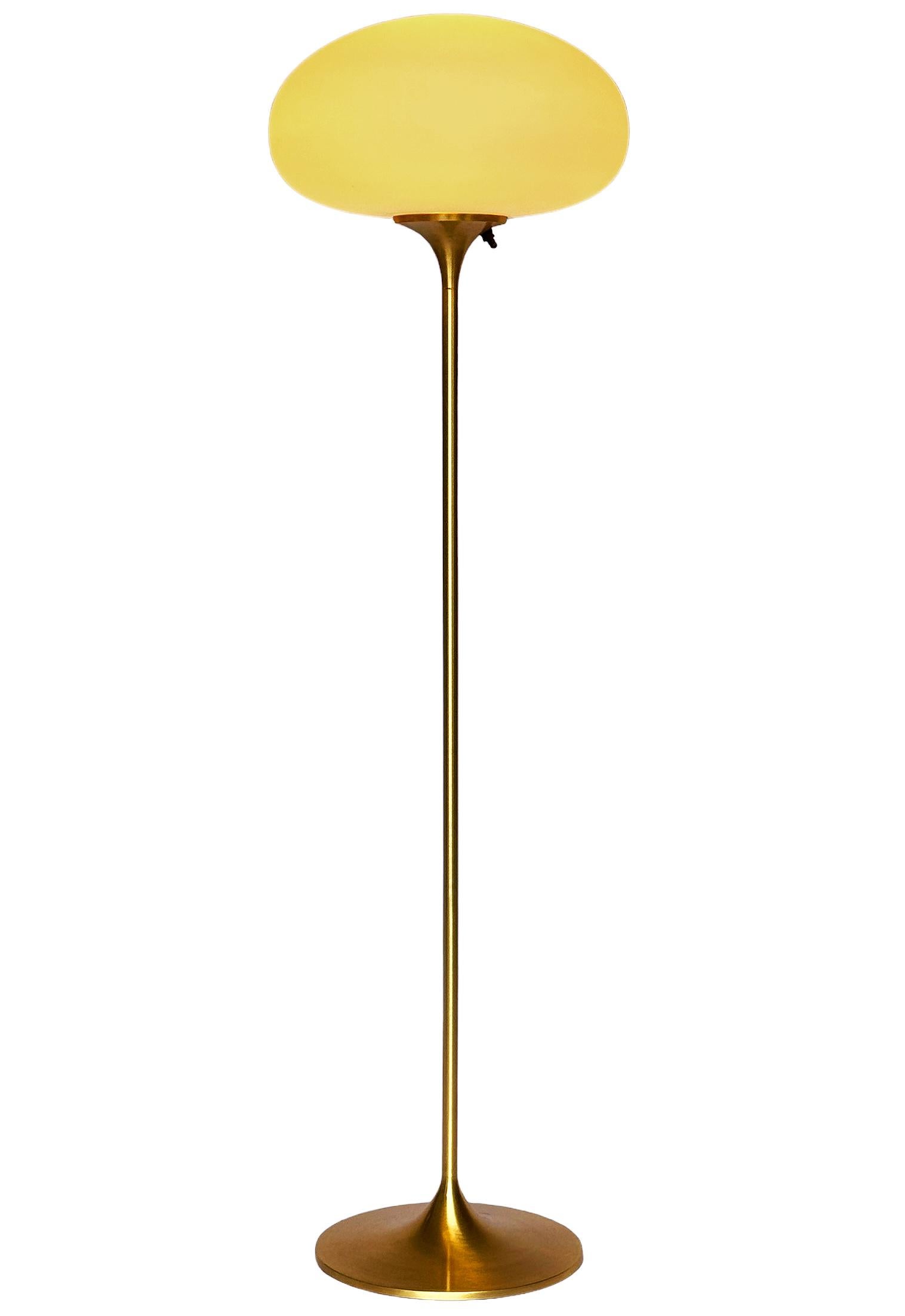 Un elegante pavimento a basso profilo realizzato da Design/One. Presenta una base principale in alluminio fuso a forma di tulipano scultoreo. La base è rifinita in ottone spazzolato/oro. La lampada in vetro smerigliato è soffiata a mano ed emana una
