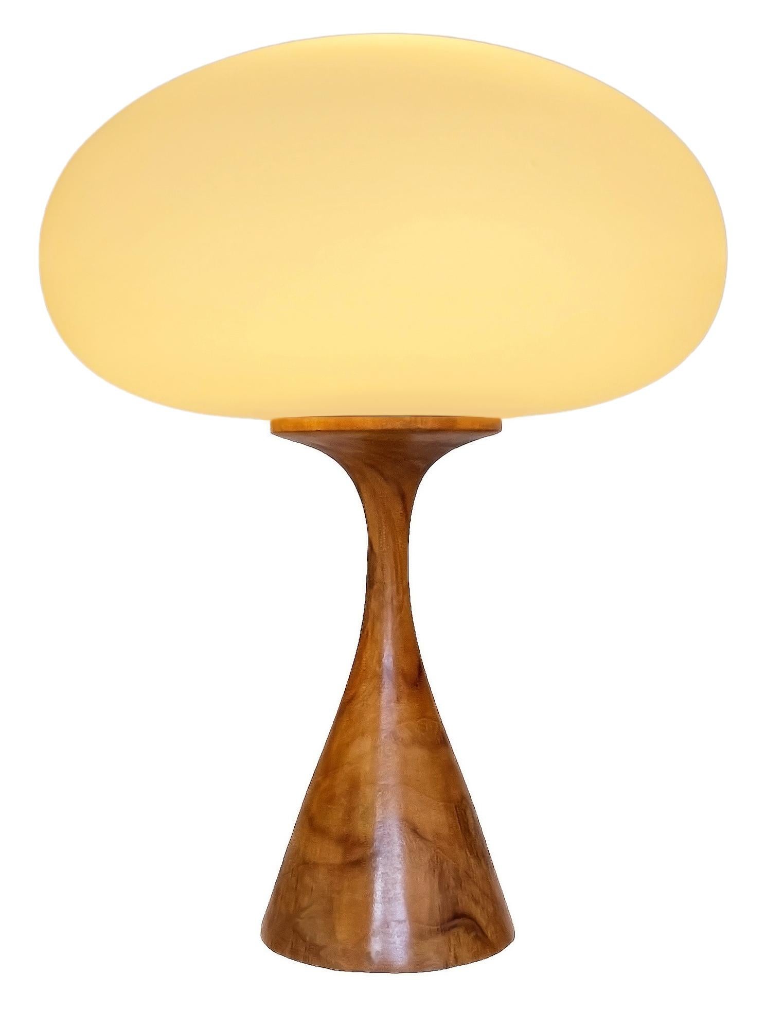 THIS ITEM IS ELIGIBLE FOR FREE SHIPPING!

An artisan handmade table lamp by Design Line. It features a solid turned teak wood base with a handblown frosted white shade which gives off a soft warm light. The wood is natural teak, so color variations,