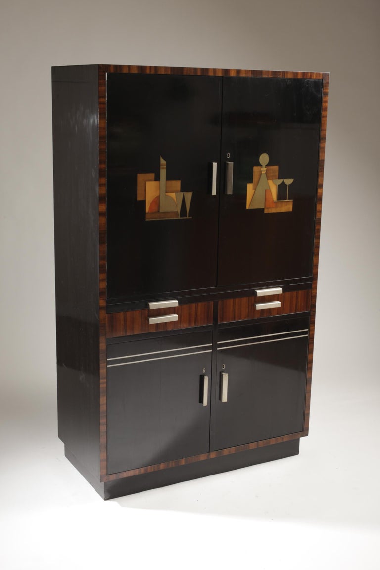 A rare bar cabinet designed by Sten Blomberg for Firma David Blomberg, Swedish Art Deco / 1930s. Inlays of metal and wood. 

Beautiful red colored interiors of the cabinet. Bottle holders and drawers, handles in wood and brushed steel. 

With