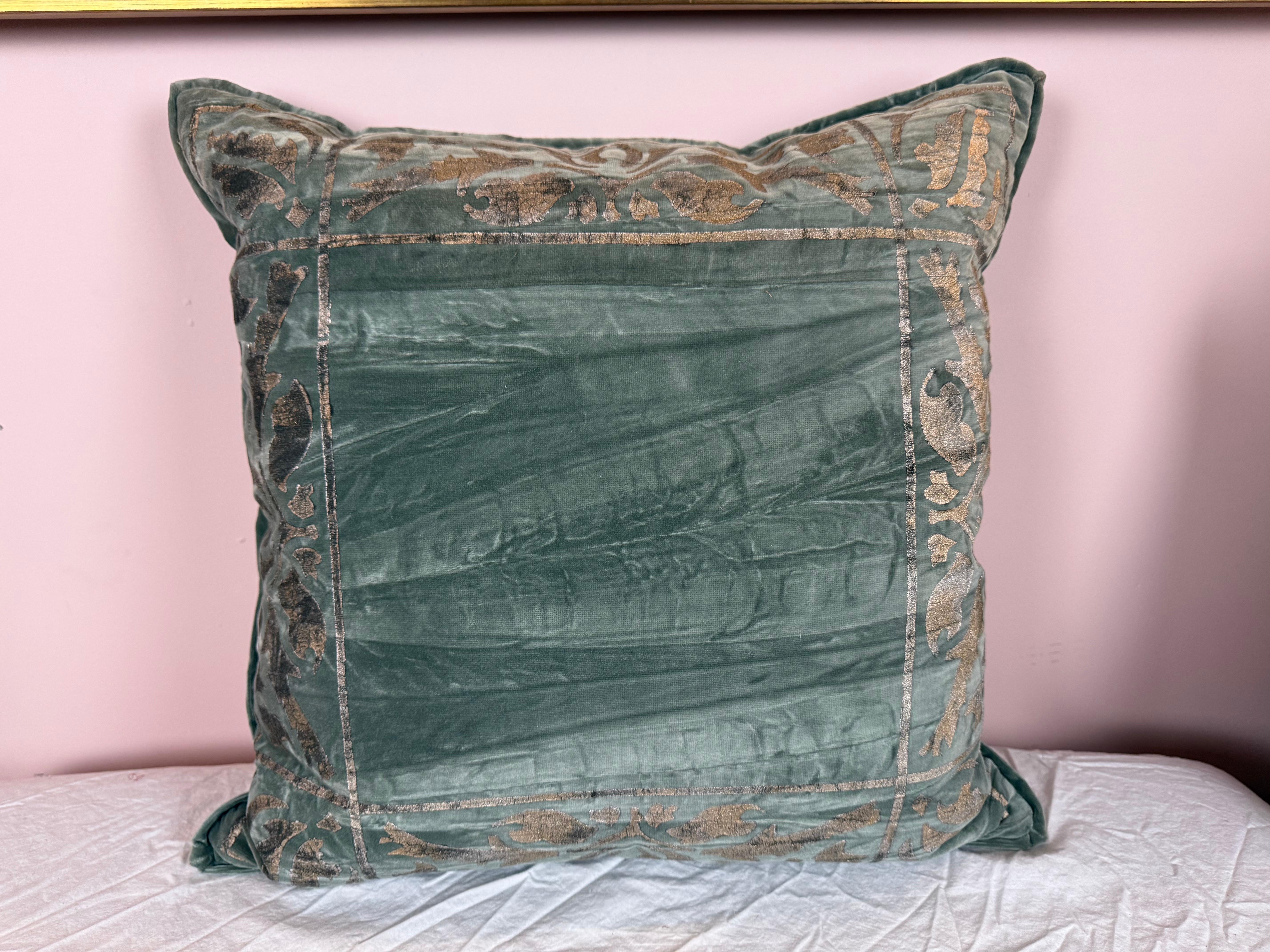 Questo sontuoso cuscino di Nomi Textiles è realizzato in morbido velluto blu-verde ed è caratterizzato da un raffinato design decorato a mano che conferisce un'aria di eleganza senza tempo. Il lavoro di stencil decorativo è reso in una tonalità