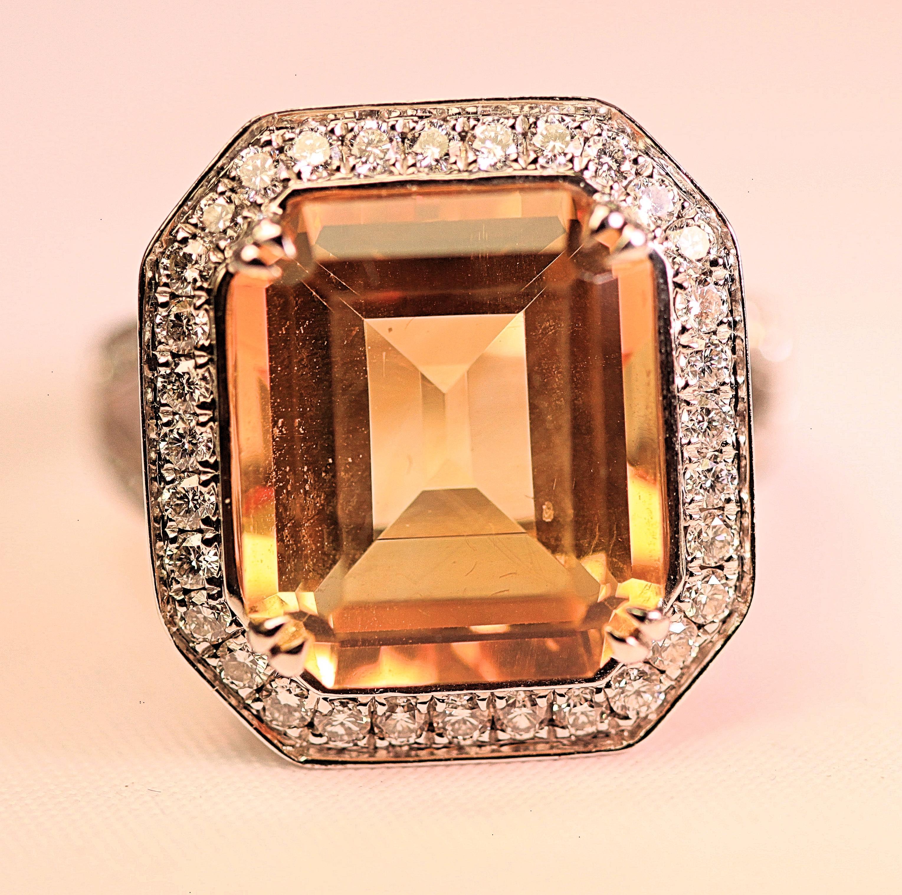 A beautiful citrine and diamond ring that is 18K white gold .  The citrine is a step-cut design that is surrounded by white diamonds. The citrine is 9.56 carats total weight. The citrine measures 14mm by 11mm. The diamonds are 1.08 carats total