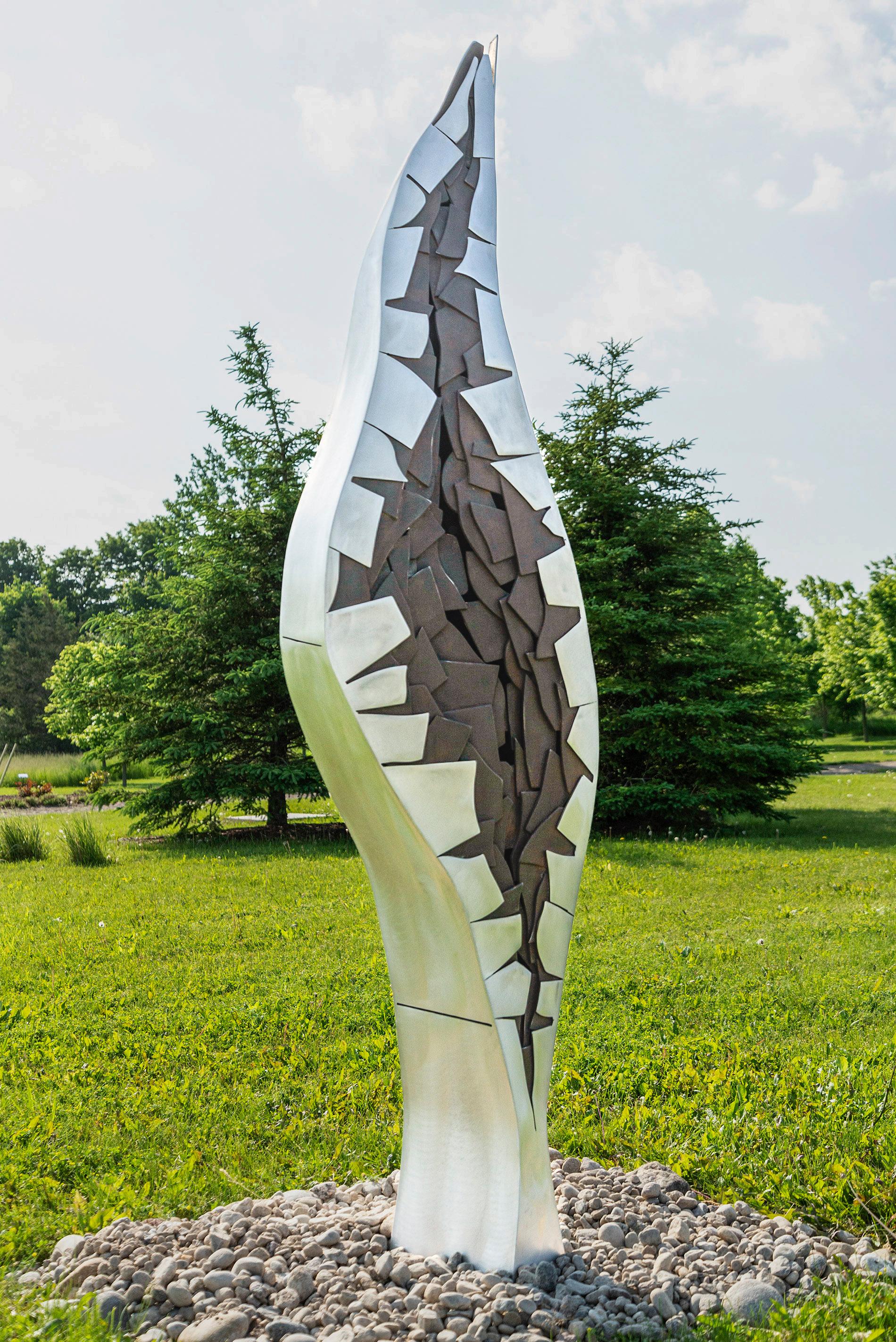 Elegantes curvas crean una imponente escultura en esta nueva obra del artista quebequés Stéphane Langlois. La columna, cortada y soldada en aluminio, se estrecha al llegar a una aguja. El centro presenta un detallado dibujo de fisuras; el metal