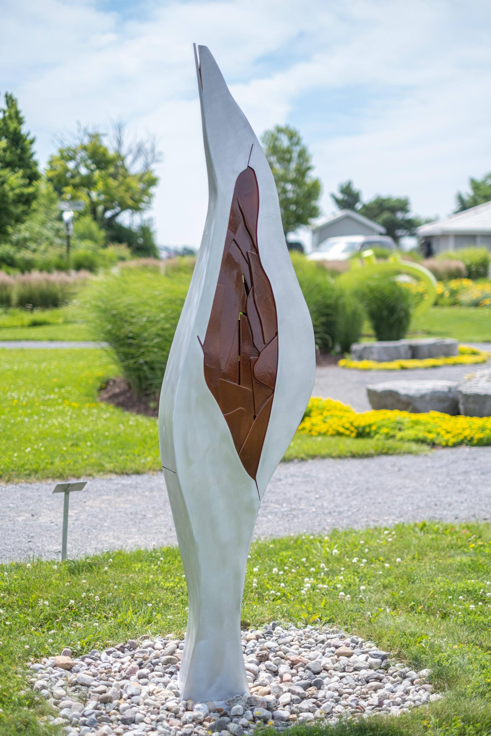 Curve eleganti creano una scultura imponente in questa nuova opera dell'artista del Quebec Stéphane Langlois. La colonna, tagliata e saldata in alluminio, si restringe fino a raggiungere una guglia. Il centro presenta un dettagliato motivo di
