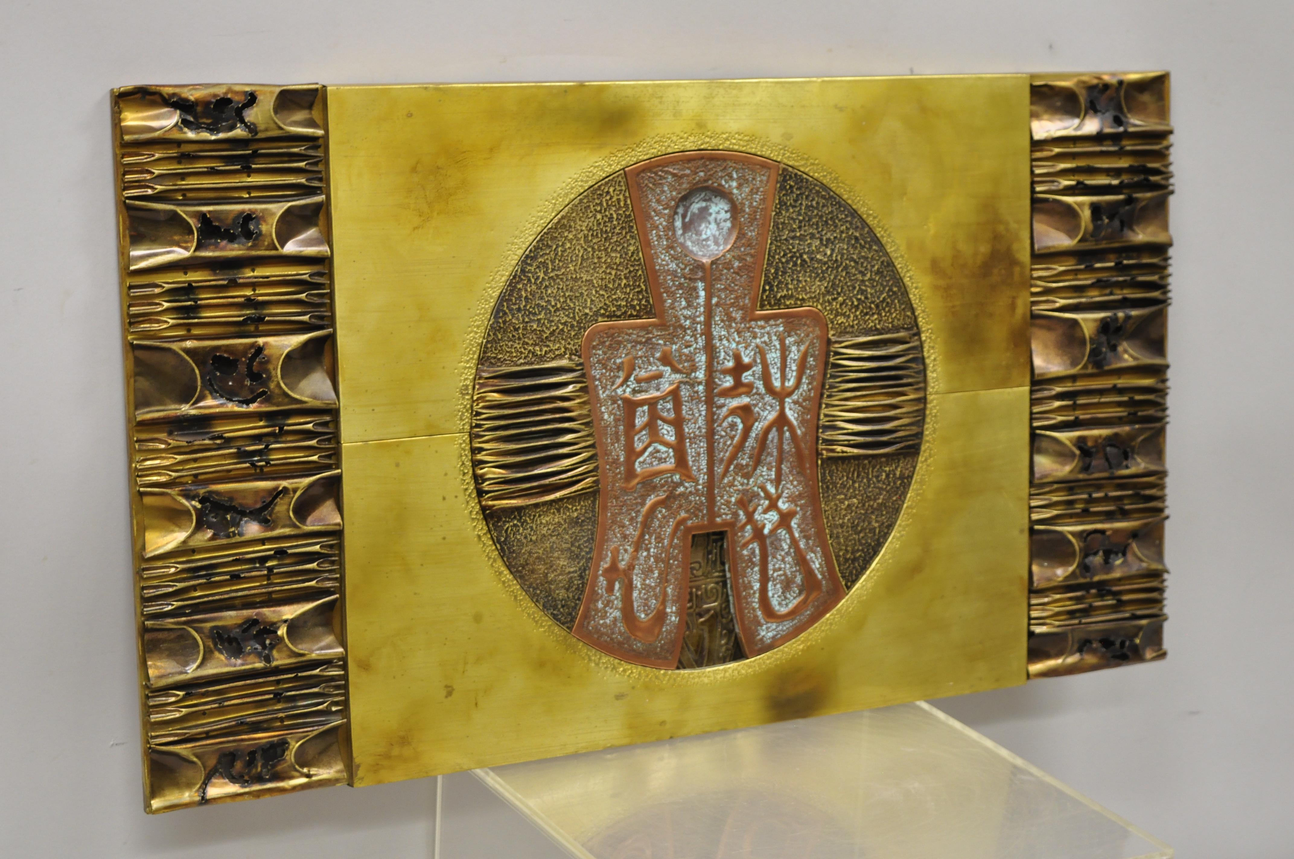 Stephen Chun attributed Brutalist torch welded brass copper wall decor art plaque. Item features brass and copper wrapped wood frame, torch welded accents, central medallion. Unsigned. Attributed to Stephen Chun, circa 1970s. Measurements: 20
