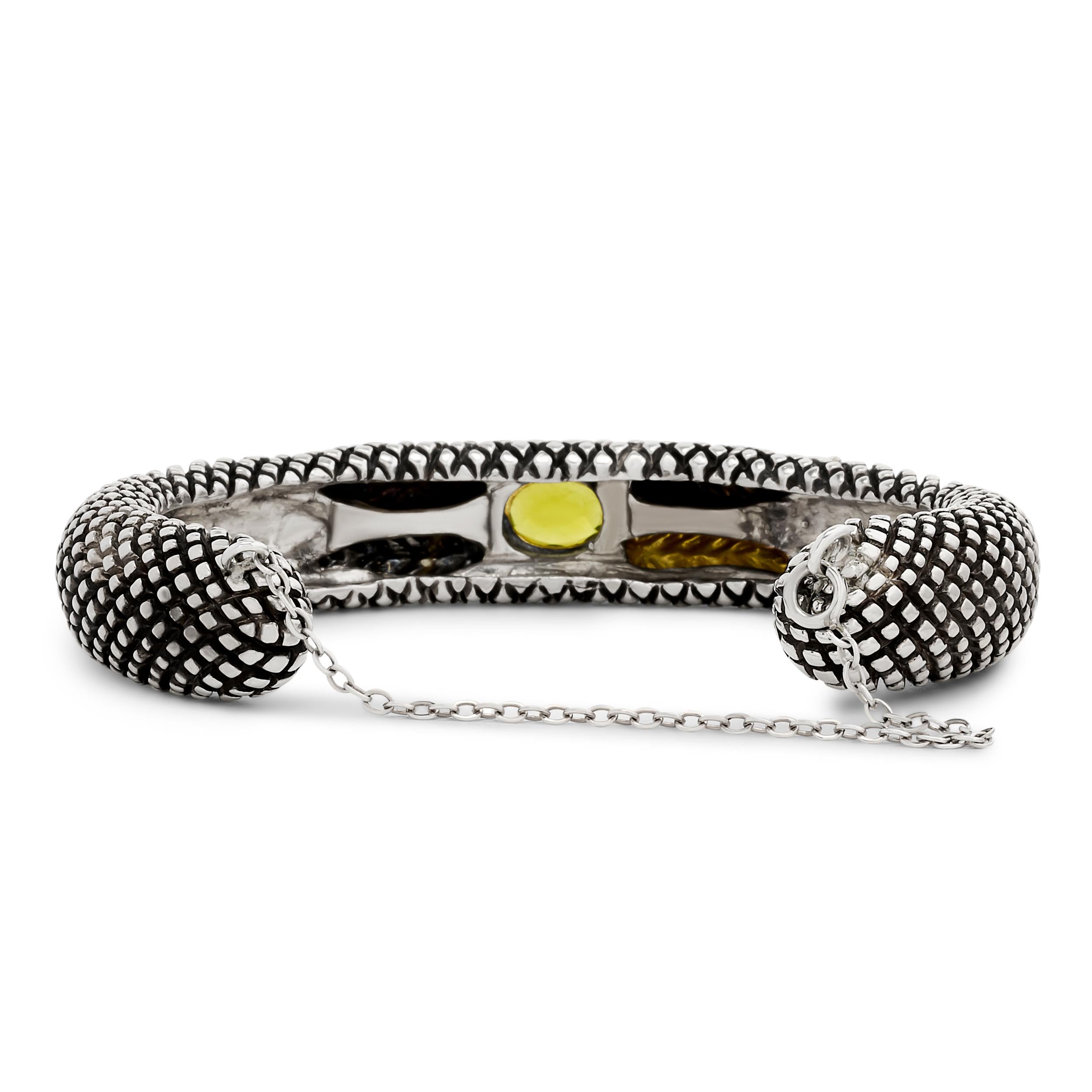 Diese Manschette von Stephen Dweck zeigt ein florales Design aus Sterlingsilber, das mit 18-karätigem Gelbgold und leuchtenden Peridot-Perlen akzentuiert ist - ein Statement mit einem Hauch von böhmischer Eleganz.

Signiert 