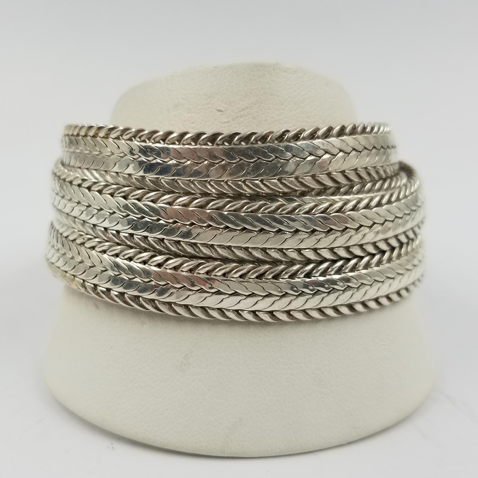 This wide bracelet is crafted in sterling silver with 18 karat yellow gold accents by designer Stephen Dweck. It is comprised of 5 individually braided rows that come together at the toggle clasp. Total length is 7.5 inches.  The bracelet can be