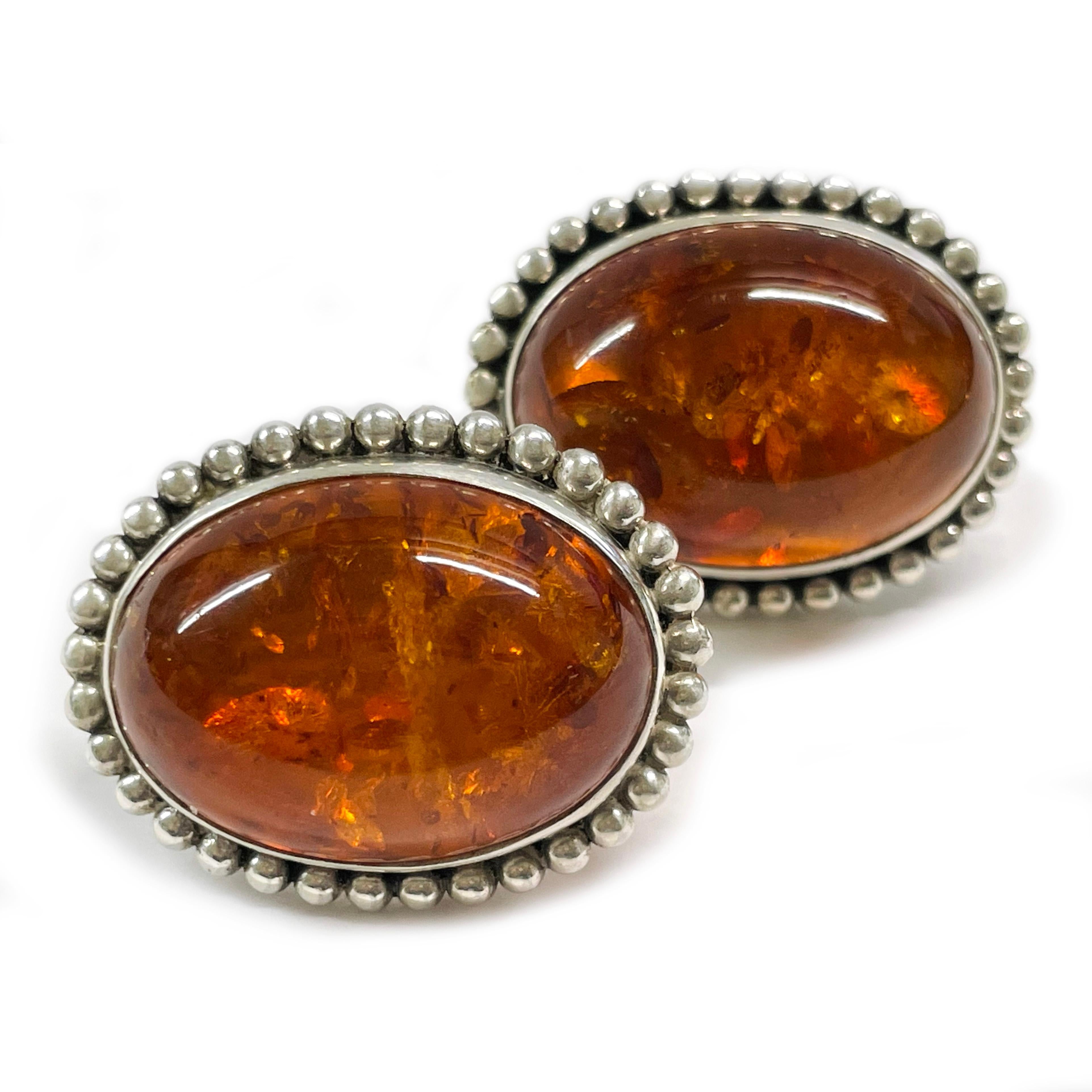 Stephen Dweck Sterling Silver Baltic Amber Earrings. The large oval Baltic Amber cabochon is bezel-set with a beaded surround. The Amber cabochon measures approximately 25 x 18mm. The earrings measure approximately 30.7mm in height x 24.2mm in width