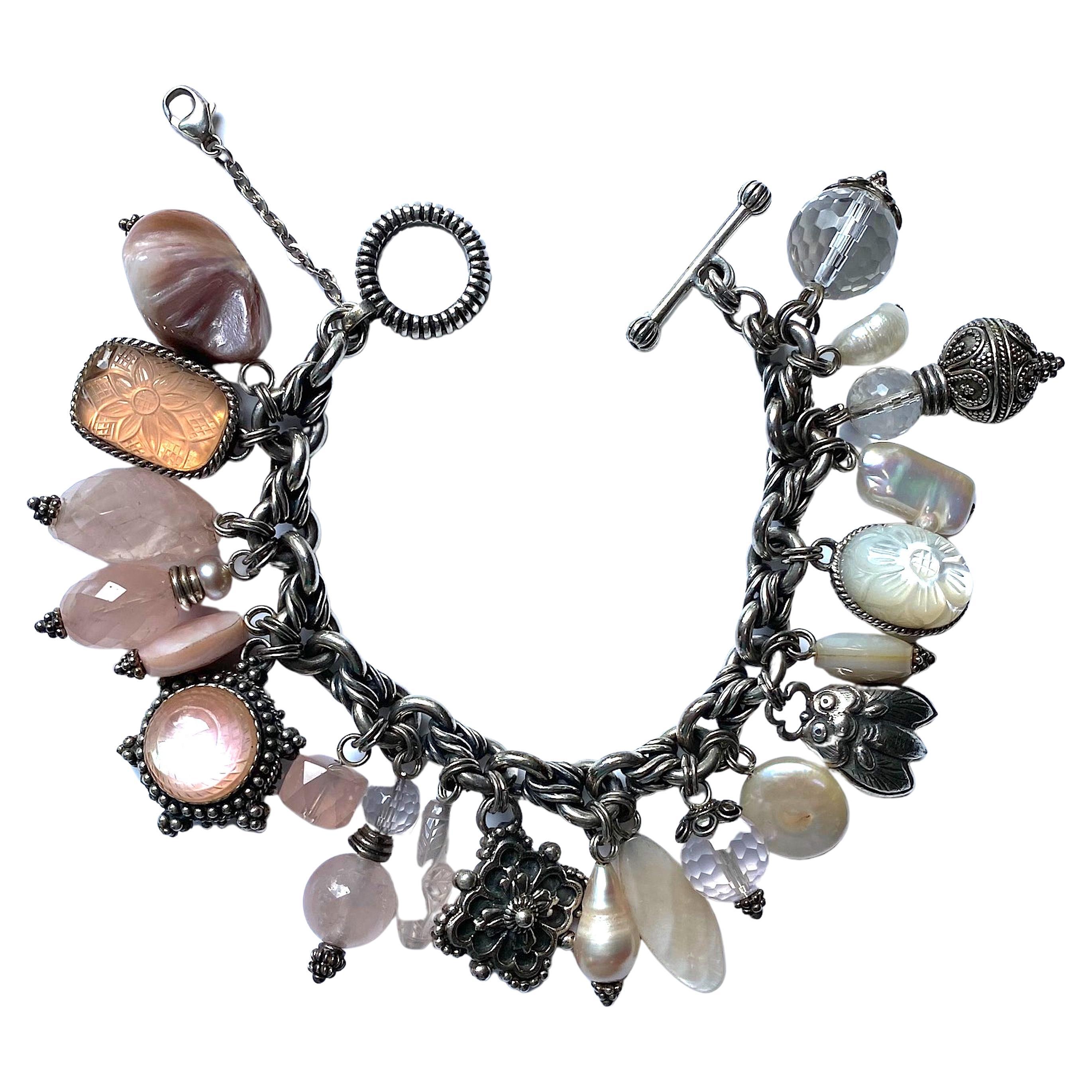 A lovely and fully loaded charm bracelet by famous jewelry designer Stephen Dweck. It features various size and shape faceted rose quarts and rock crystal bead, natural biwa and fresh water pearls, mother of pearl and sterling silver charms. The