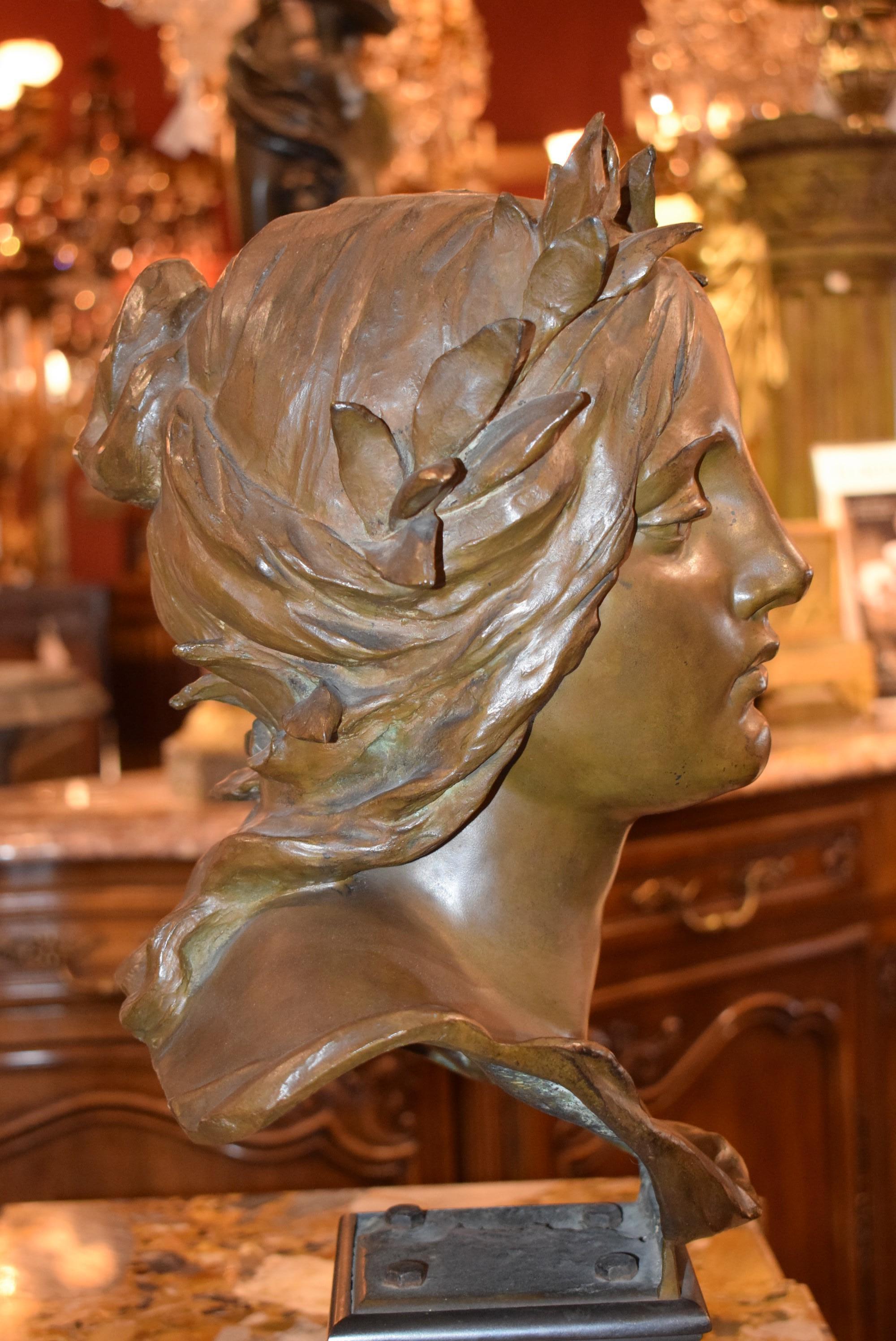 Bronze bust length sculpture depicting a woman with a 10 laurel wreath in long hair with calm and composed facial expression on a classical base. CW4708