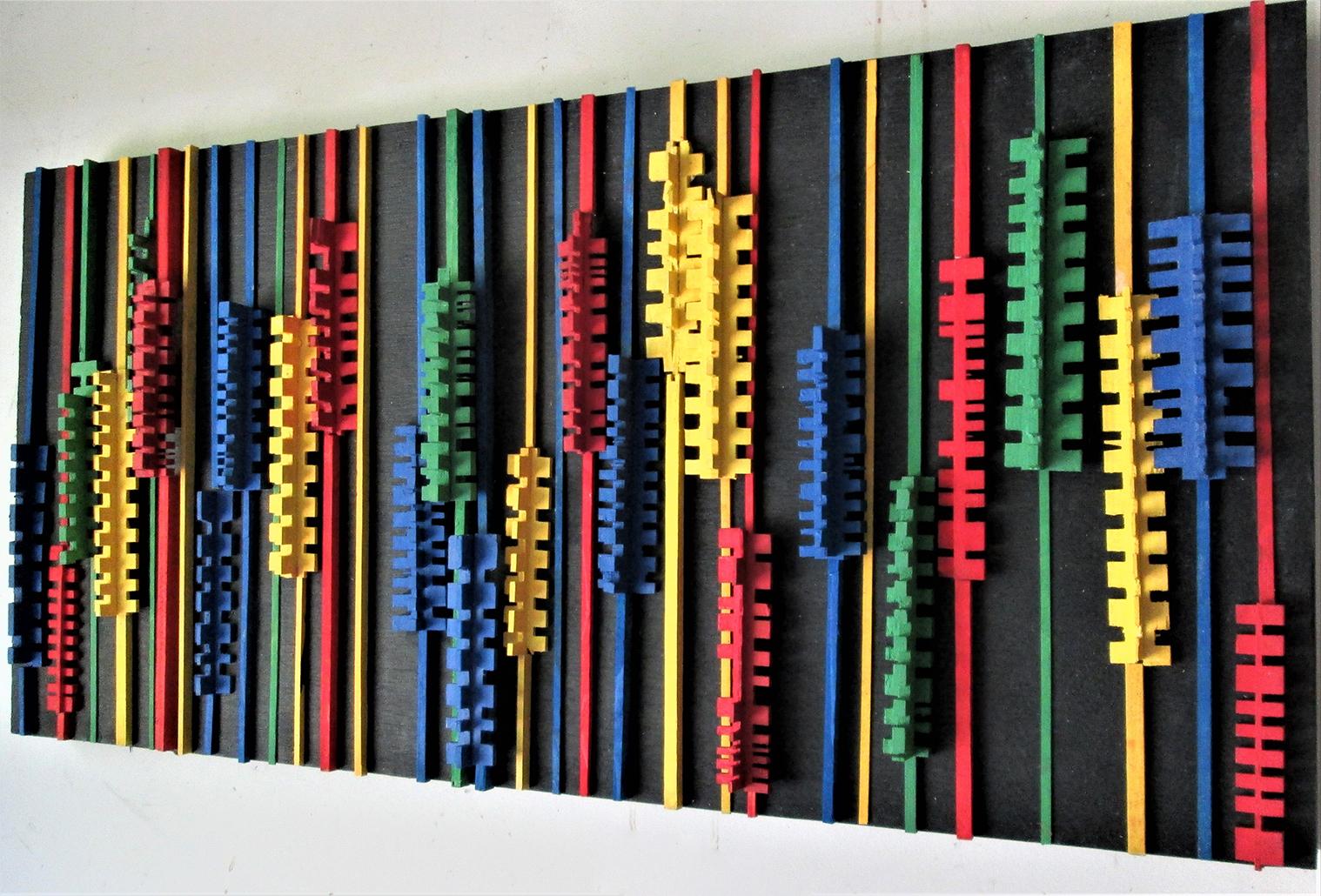 Abstract geometric three-dimensional wood wall sculpture in bright yellow, blue, red, and green on black
Bloomin', made by Hudson Valley artist, Stephen Walling, in 2020
18 x 37 inches, carved and painted wood on wood panel
Wire backing for secure