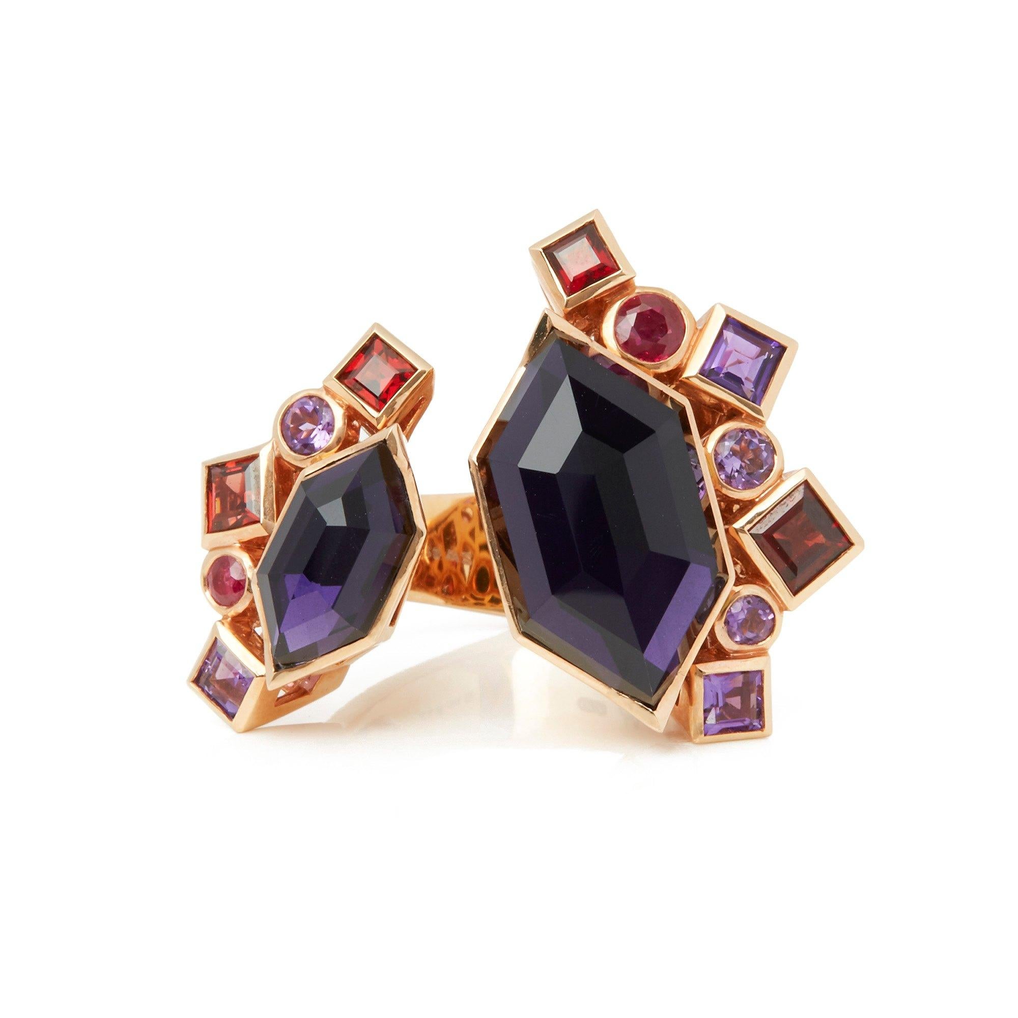 This Ring by Stephen Webster is from his Crystal Haze Gold Struck Collection and features Two Synthetic Amethyst set sections Totalling 9.65cts Surrounded with mixed cut Amethyst, Red Garnets and Rubies. Set in 18k Yellow Gold with Signature Stephen