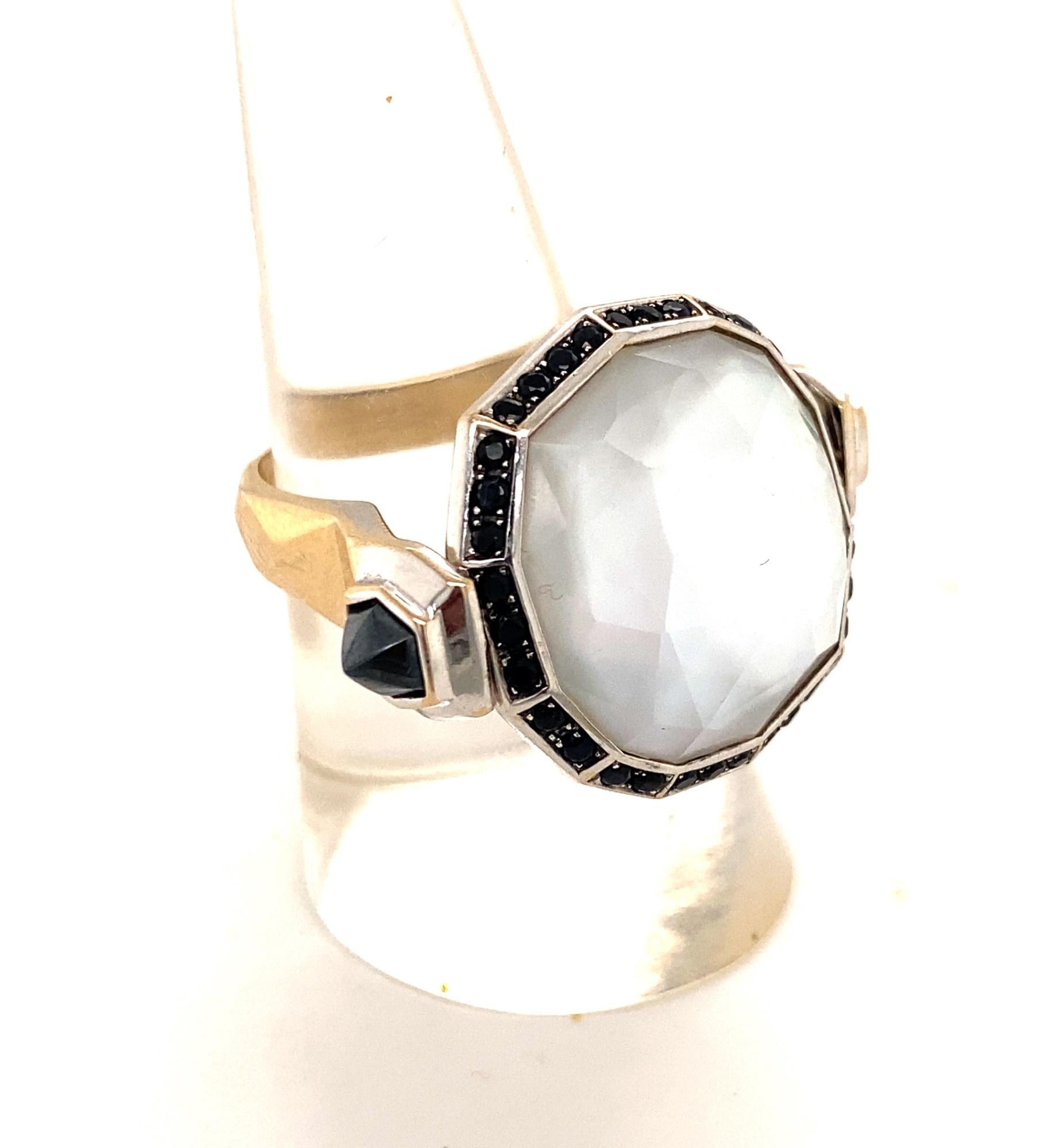 This is a beautiful ring made by Important English designer Stephen Webster.  The ring has a unique flip design that flips revealing fancy cut mother of pearl with black diamonds and the other side black quartz with white diamonds.  The ring is