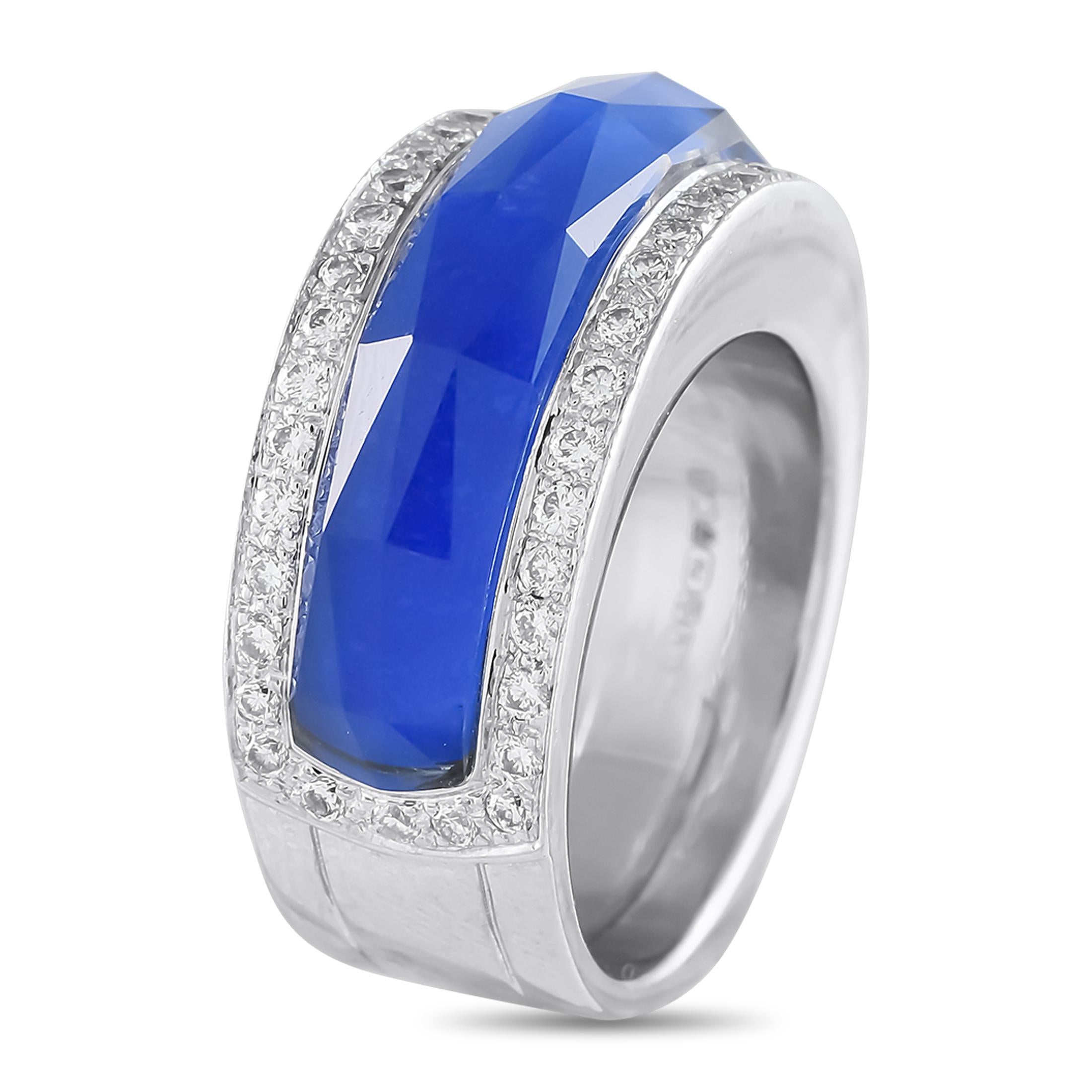 Dramatic in its deep blue elegance, this Stephen Webster creation is bound to impress. It has a wide band fashioned in solid 18K white gold. The ring features Stephen Webster's popular Crystal Haze technique, where a clear quartz crystal is layered