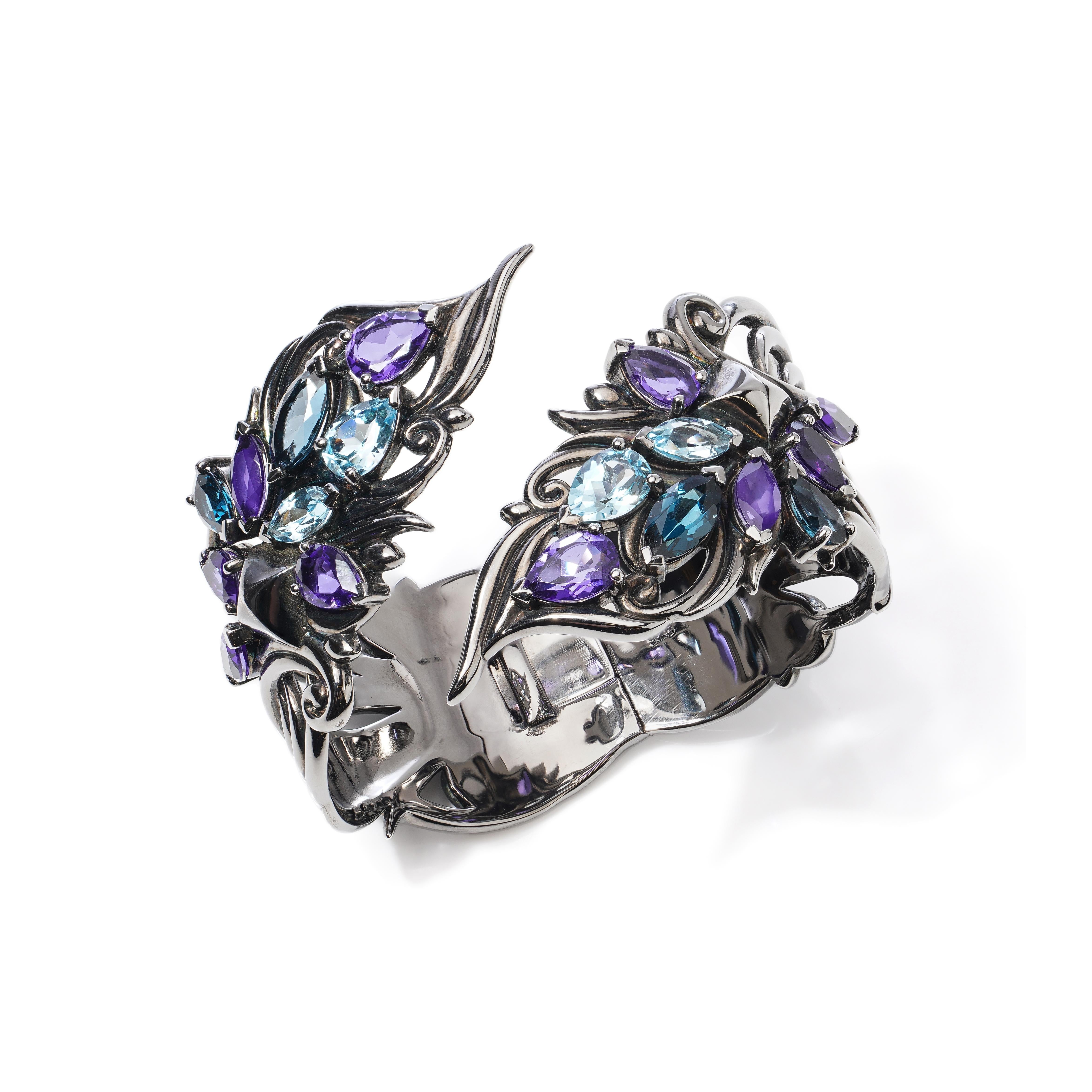 Stephen Webster Rhodium - plated  925 sterling silver cuff bangle set with Topazes and Amethyst stones.  
Maker: Stephen Webster
Made in England, 
Hallmarked 925

Dimensions -
Inner diameter  x width: 6.1 x 4.7 cm 
Weight: 109 grams 

Blue Quartz -