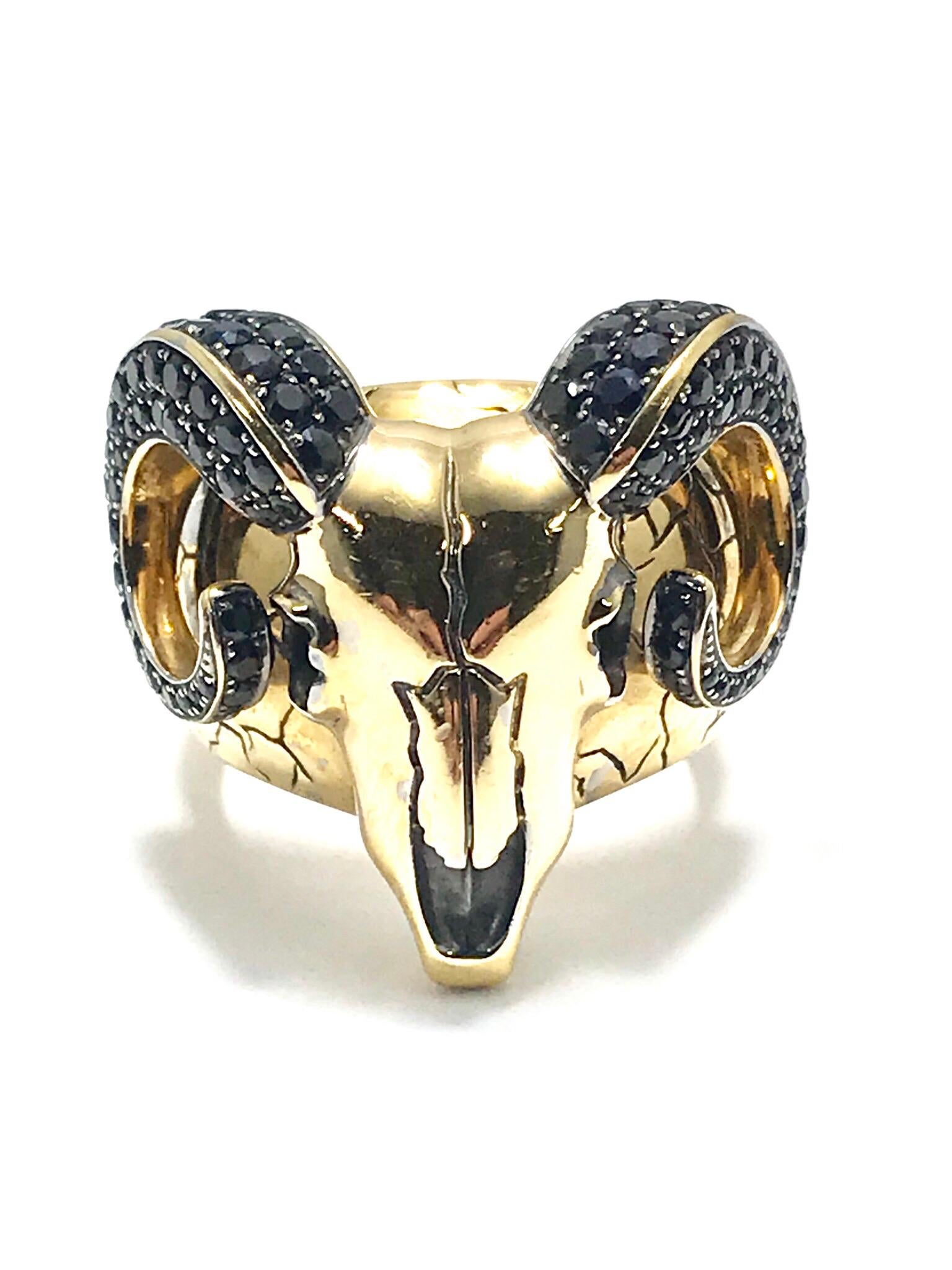 A unique Stephen Webster Black Sapphire and 18 karat yellow gold ram's skull ring.  Created with intricate detail, having the round faceted black sapphires set in the ram's horns, and an etched pattern on the tapering shank.  The horns contain 2.25