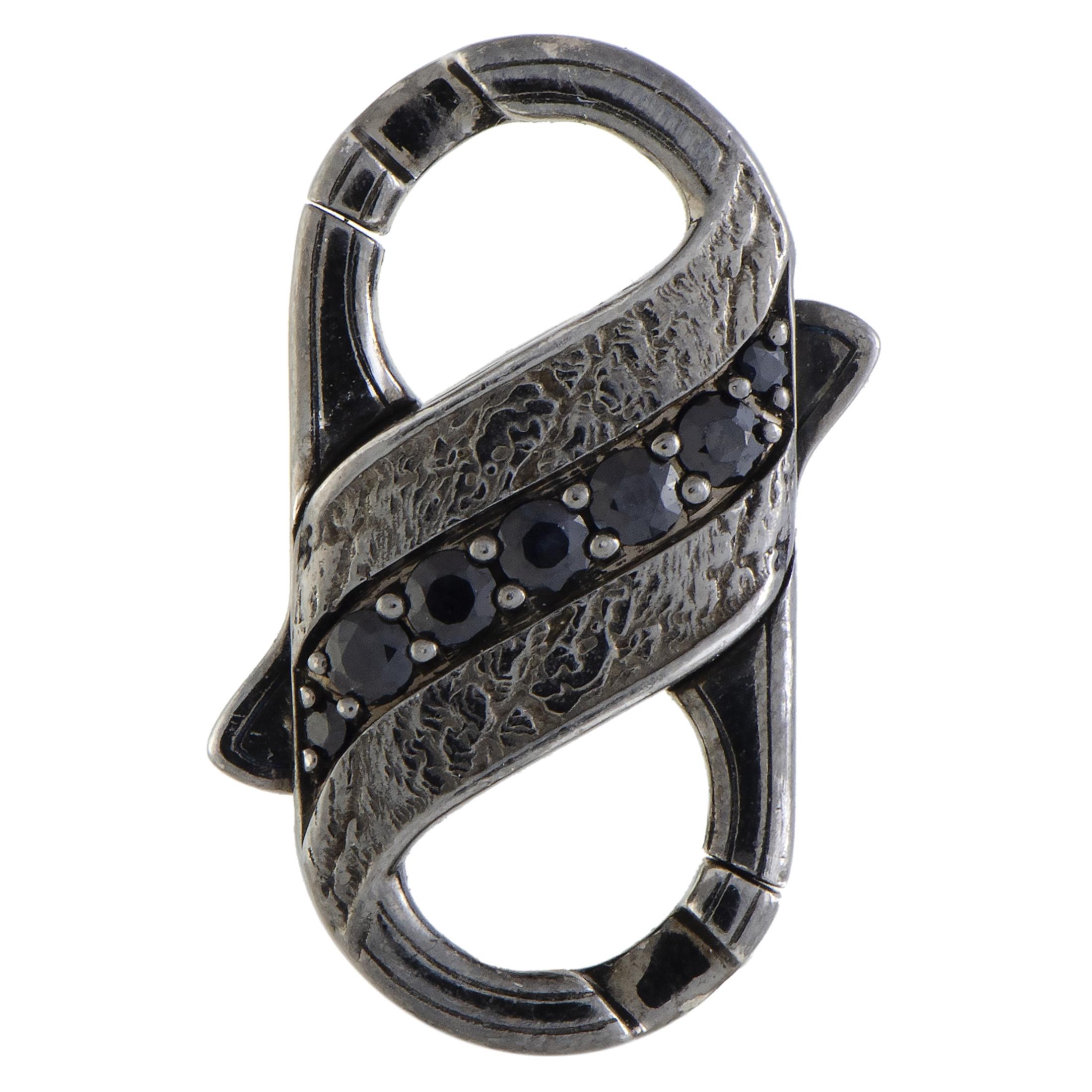 This extraordinary gentlemen’s clasp is characterized by incredibly rugged design that gives a stunningly masculine appeal to the piece, attractively accentuated by eye-catching gems. The clasp is presented by Stephen Webster within the “England